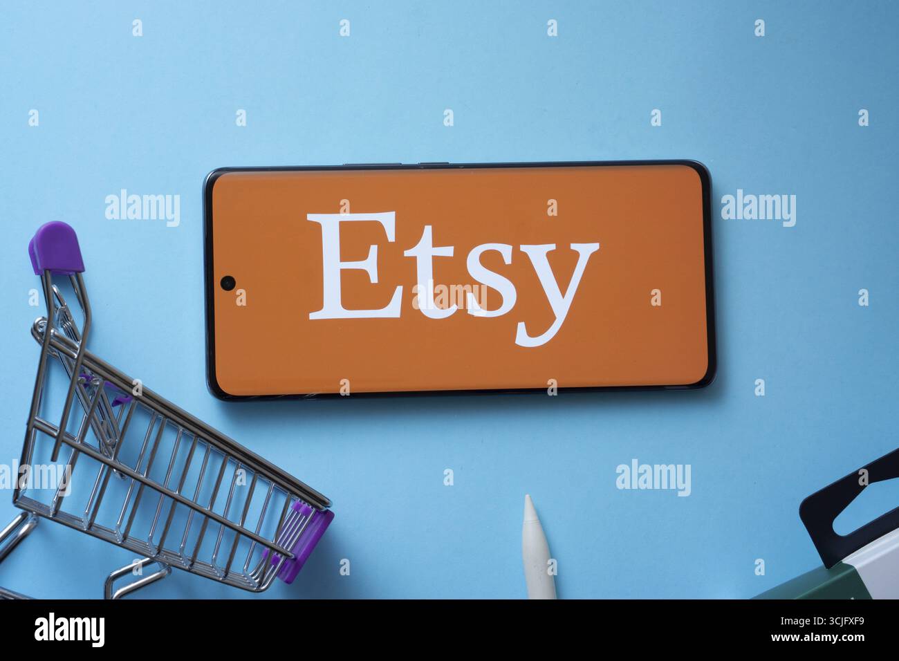 Dhaka, Bangladesch, 03. Juli 2025: Smartphone mit Etsy-Logo und Warenkorb auf blauem Hintergrund Stockfoto