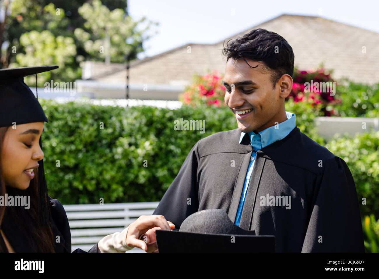 Abschlussfeiertag, verschiedene Studenten feiern Leistung im Freien, lächeln vor Freude Stockfoto