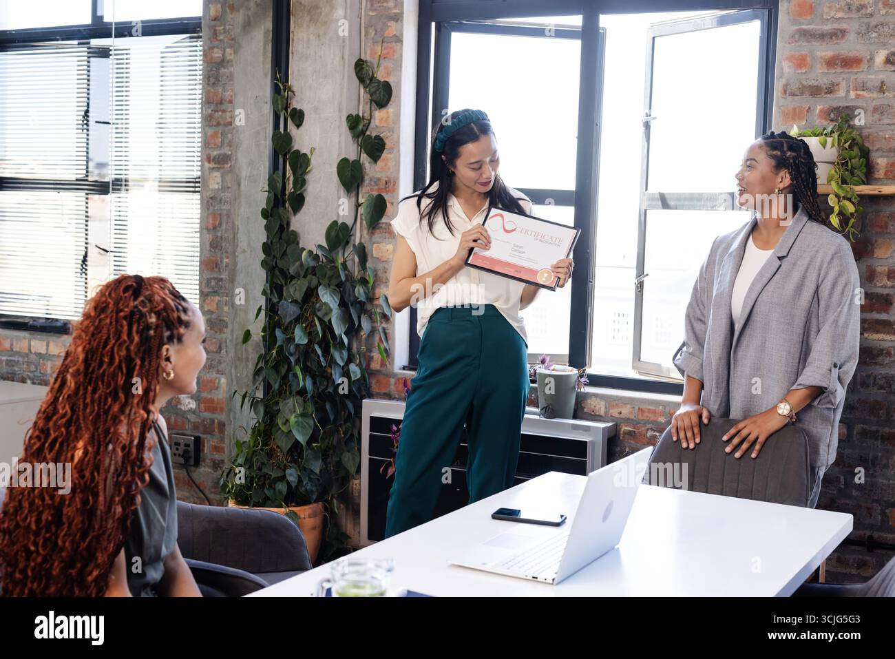 Feiert Erfolge, Kollegen im modernen Büro, Frau mit Zertifikat, lächelnd Stockfoto