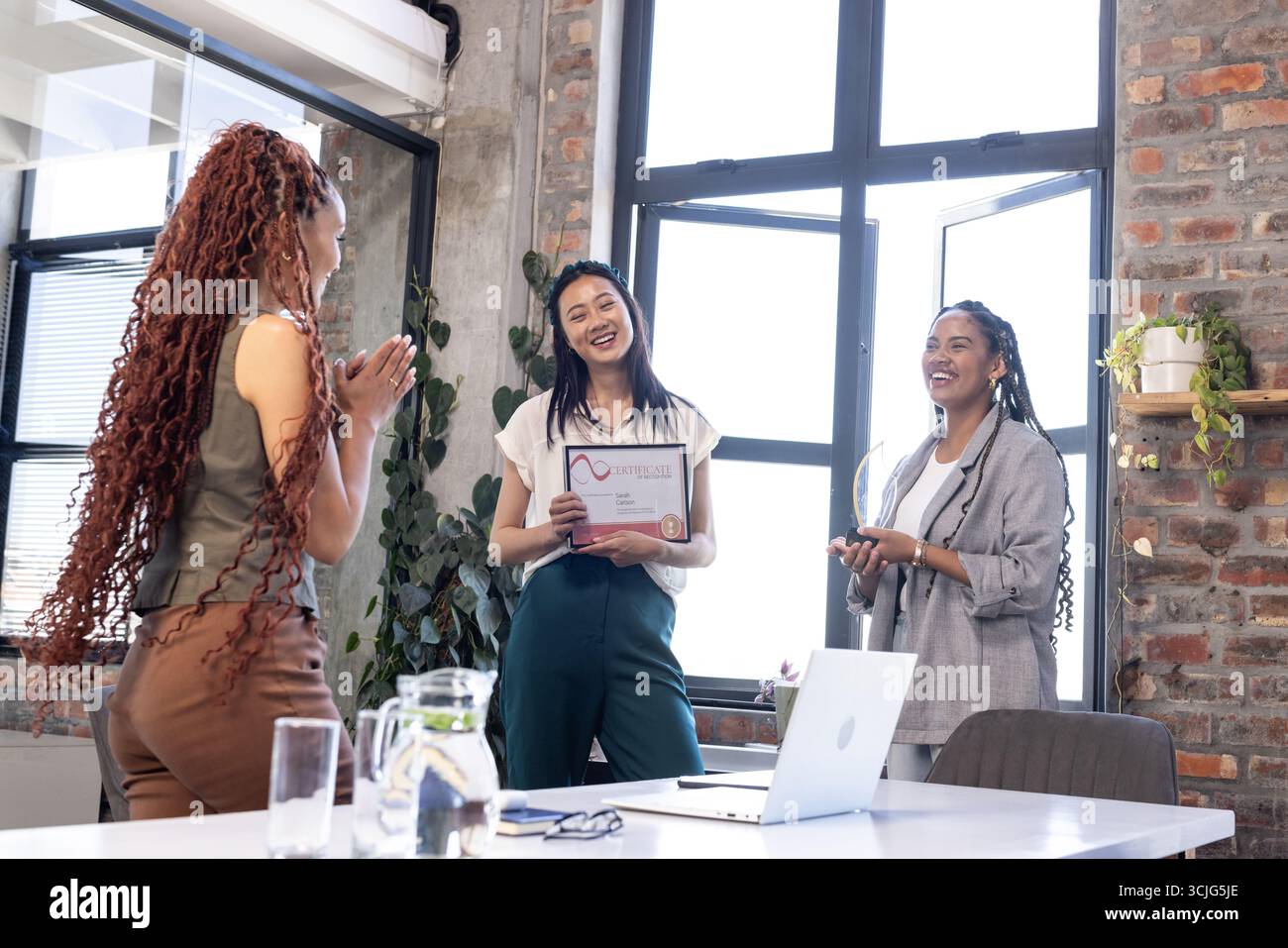 Kollegen, die geschäftliche Erfolge in einem modernen Büroumfeld mit Auszeichnung feiern Stockfoto
