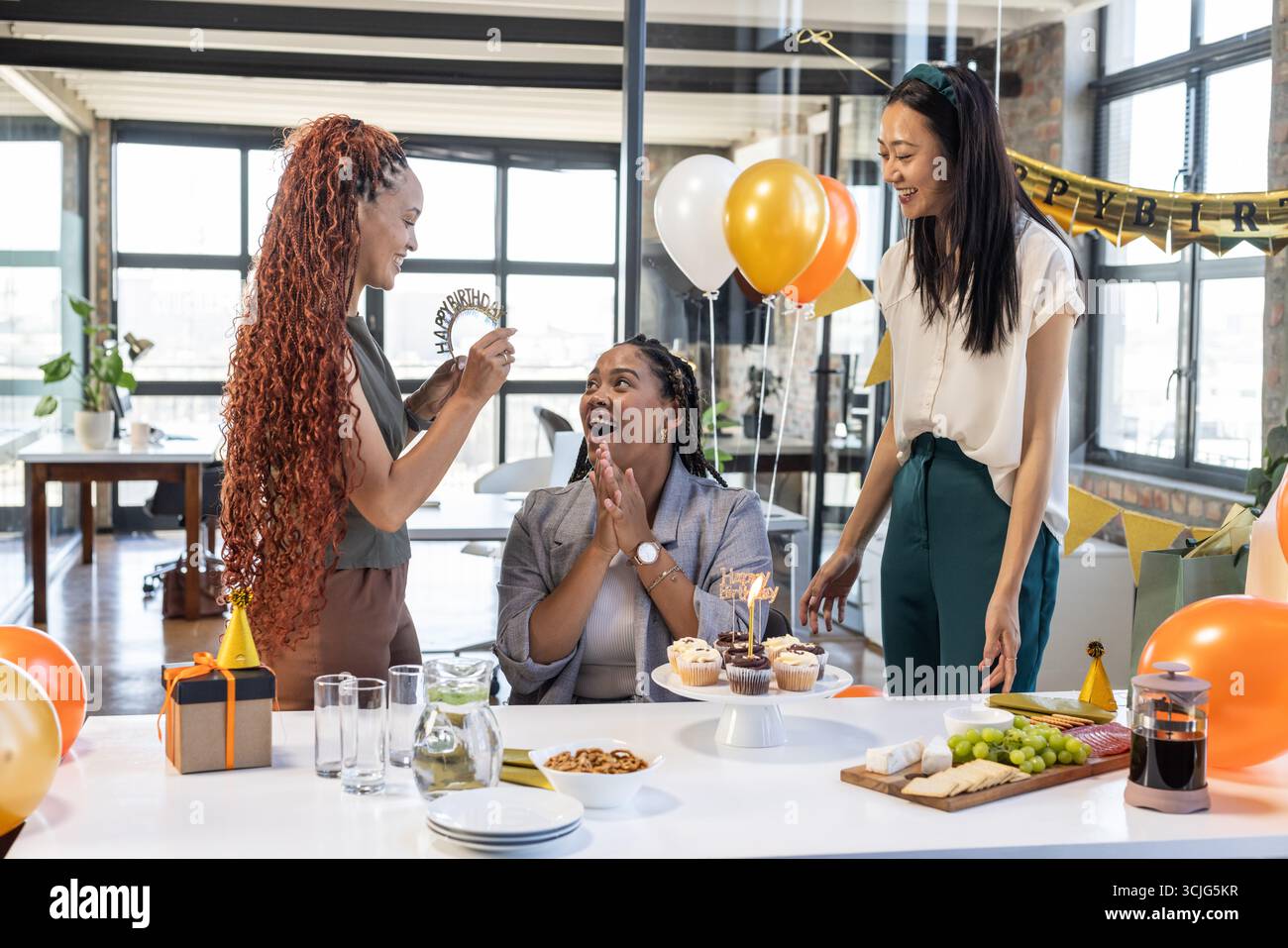 Feiern Sie den Geburtstag im Büro, Kollegen teilen sich Cupcakes und Ballons, genießen Sie Momente Stockfoto