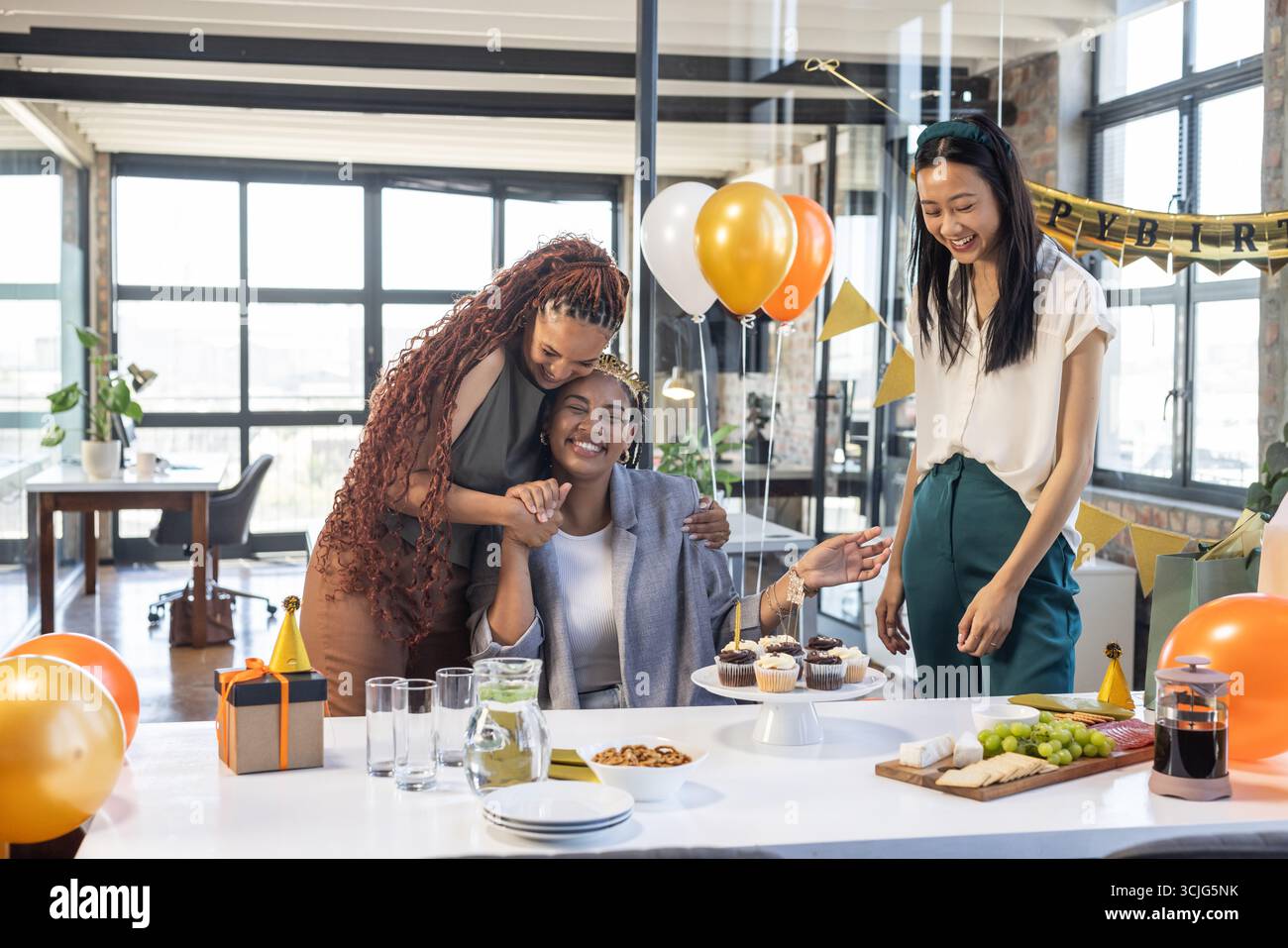 Kollegen feiern im Büro Geburtstag mit Ballons, Kuchen und fröhlichem Lächeln Stockfoto
