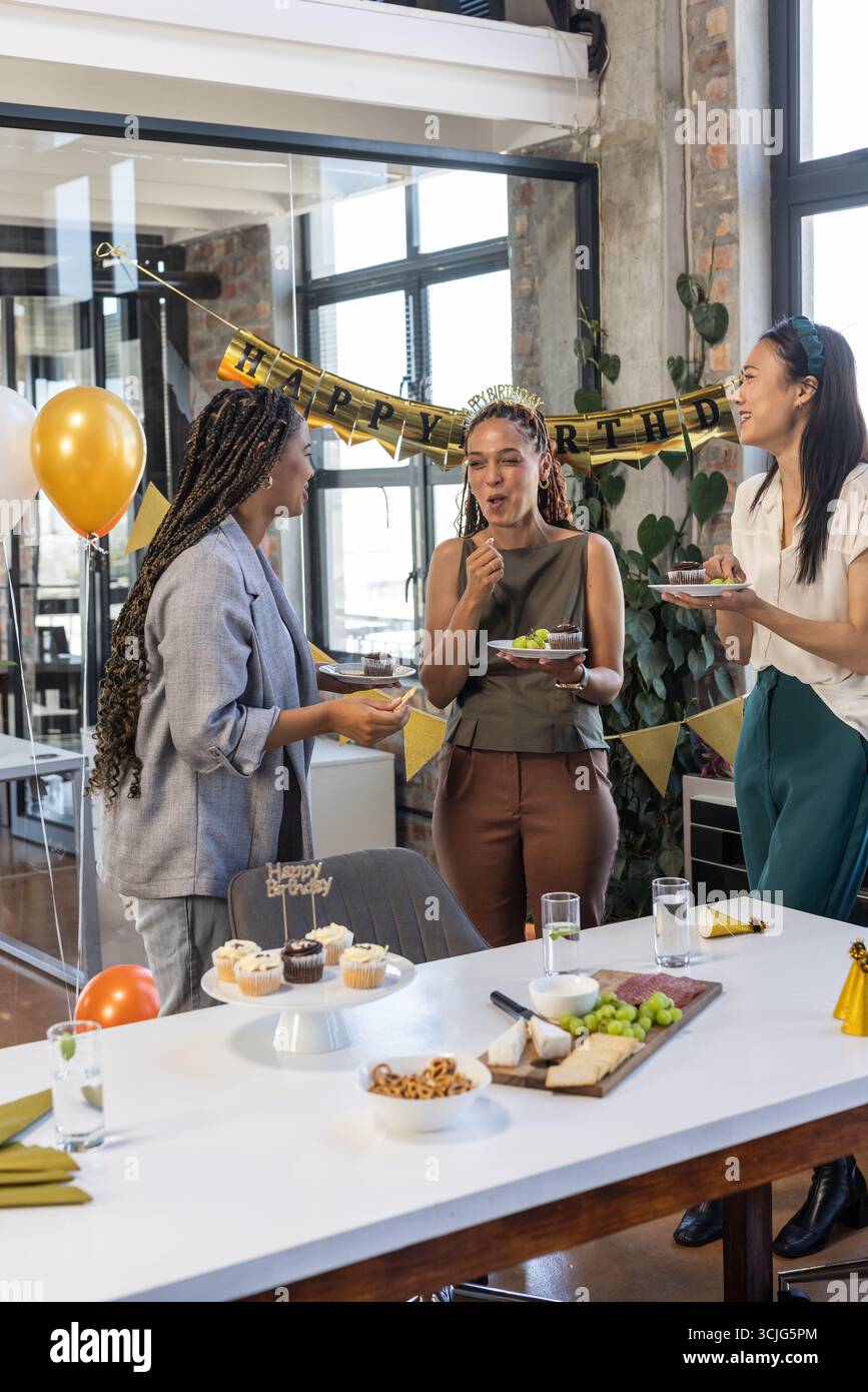 Kollegen feiern Geburtstag im Büro, genießen Kuchen und lachen gemeinsam Stockfoto