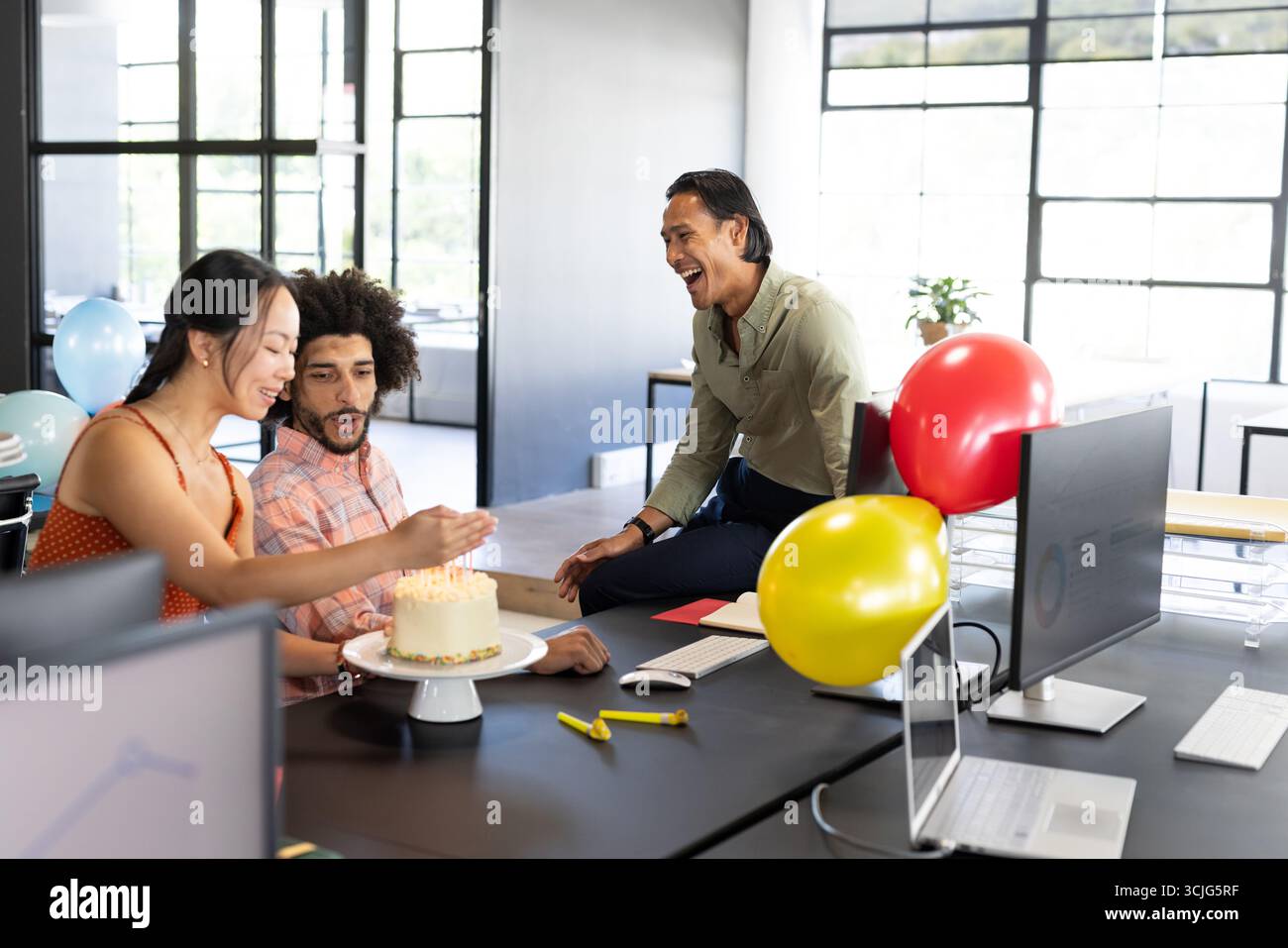 Kollegen feiern Geburtstag mit Kuchen und Ballons in moderner Büroumgebung Stockfoto