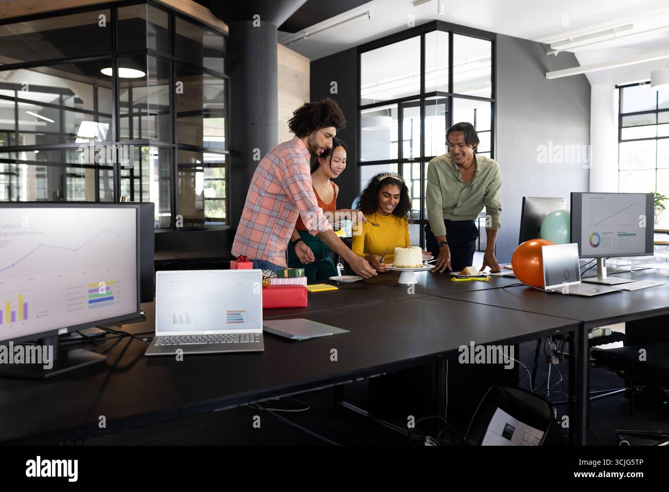 Geburtstag in einem modernen Büro, ein vielfältiges Team, das sich um Kuchen versammelt Stockfoto