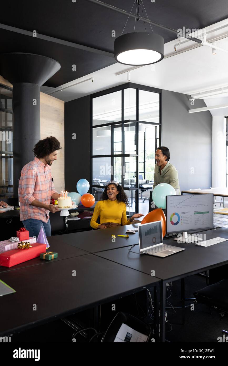 Im Büro feiern Kollegen ihren Geburtstag mit Kuchen und Ballons und lächeln fröhlich Stockfoto