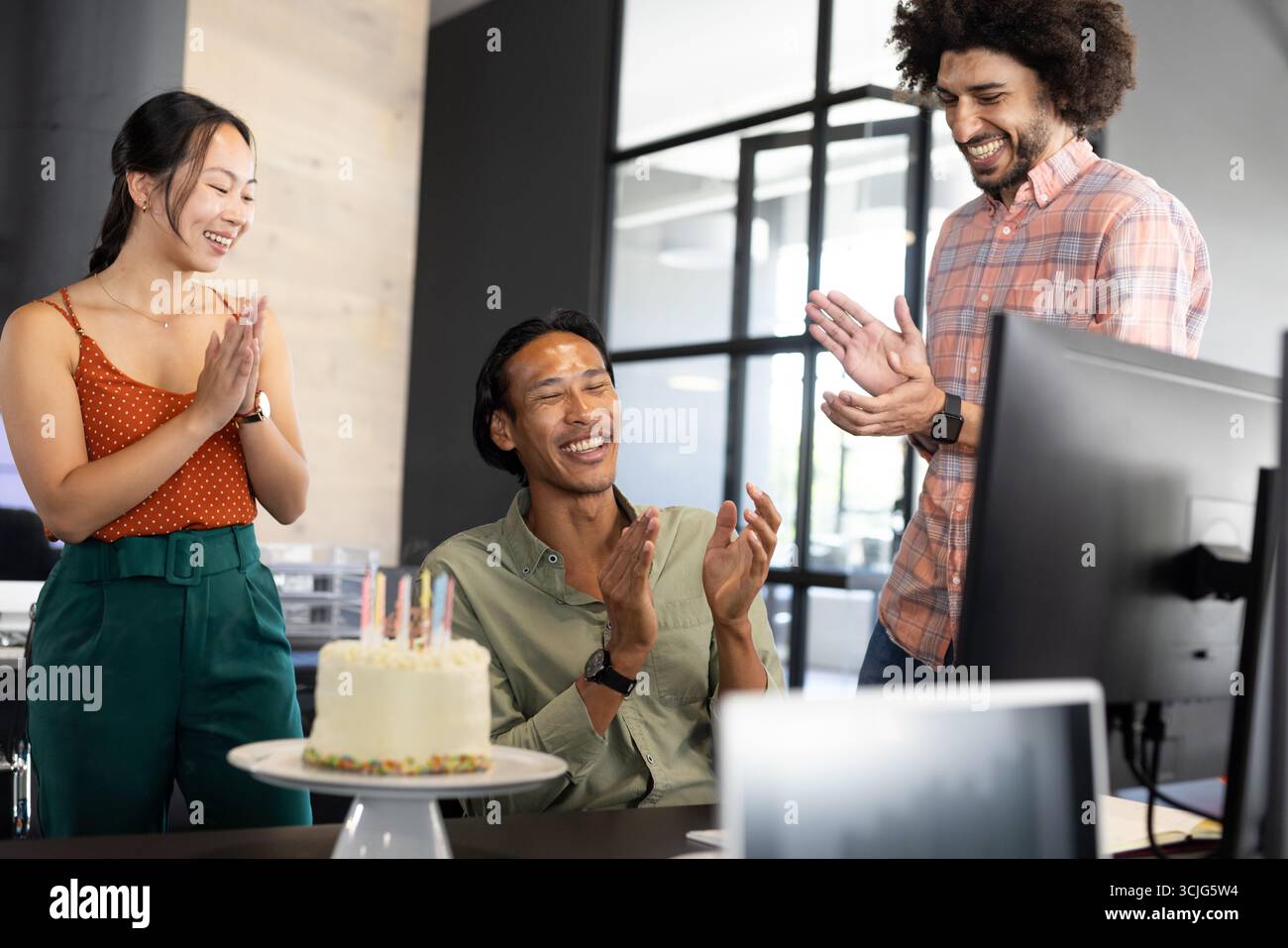 Wir feiern Geburtstag im Büro, verschiedene Kollegen klatschen um Kuchen und lächeln Stockfoto