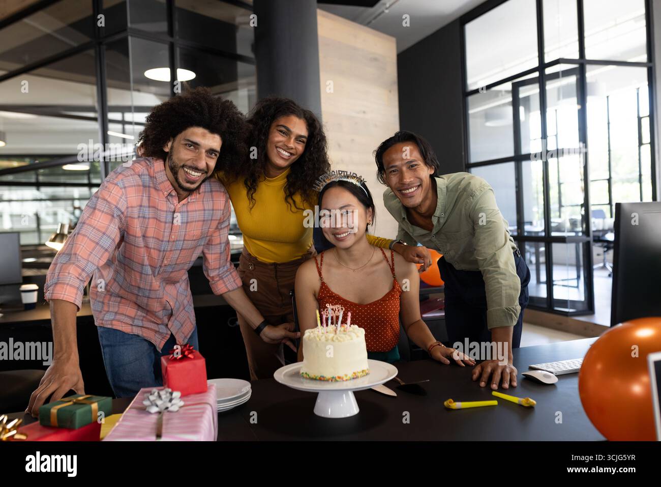 Lächelnde Kollegen feiern im Büro Geburtstag mit Kuchen und Geschenken auf dem Tisch Stockfoto