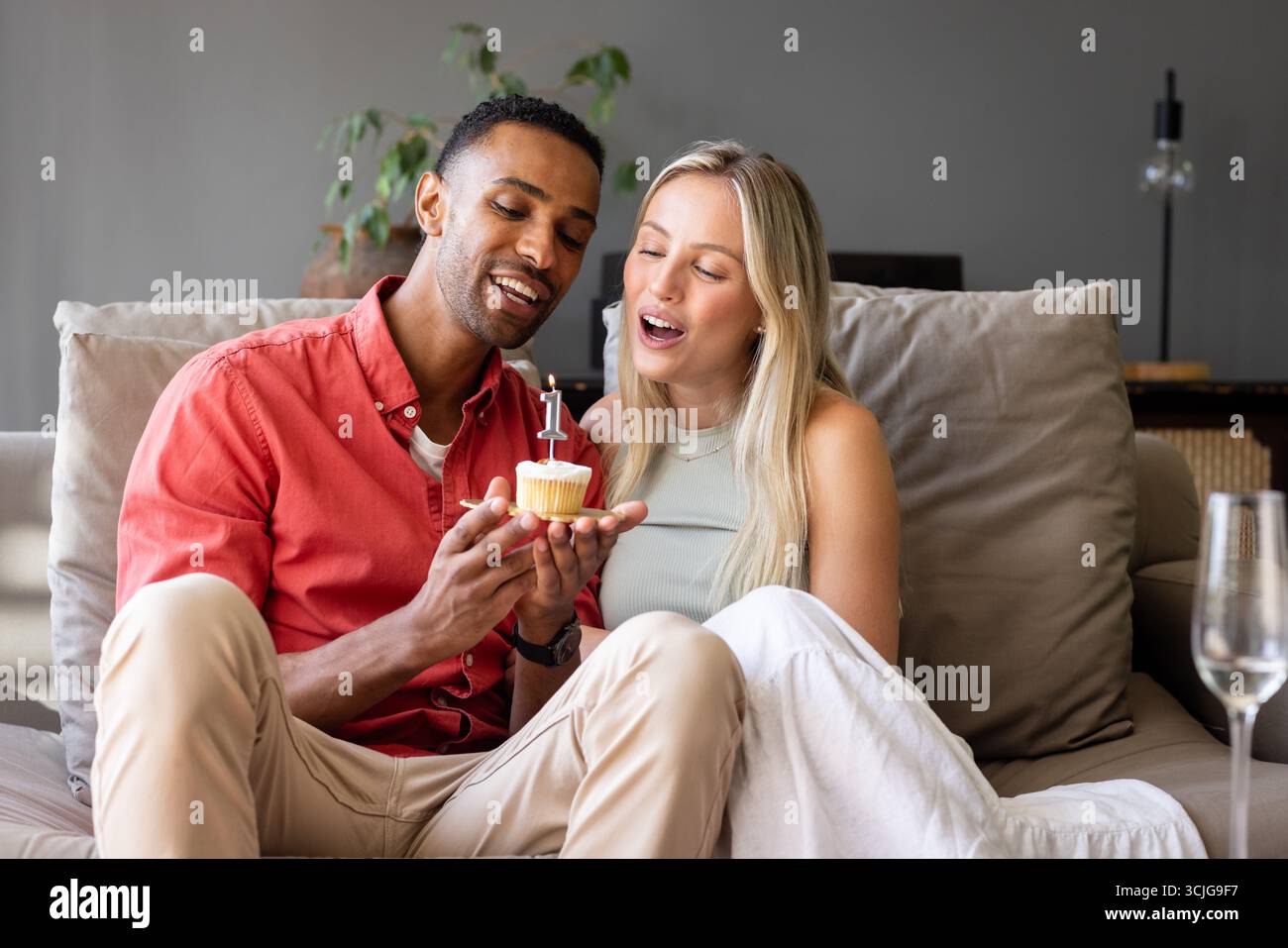 Mit Cupcake feiern, Paare lächeln auf der Couch, gemeinsam einen besonderen Moment verbringen Stockfoto
