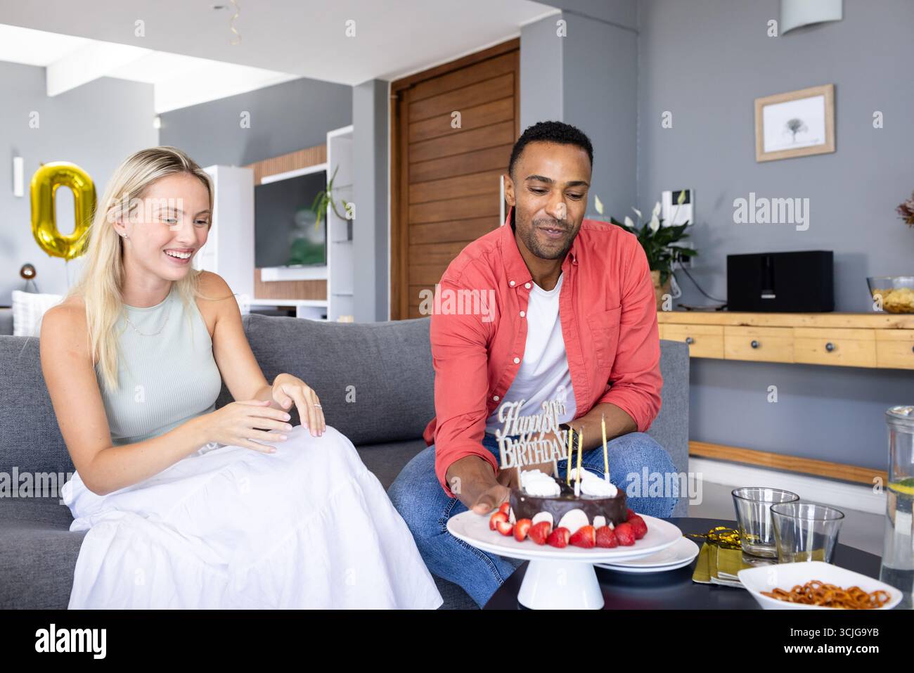 Wir feiern Geburtstag, Mann und Frau genießen Kuchen mit fröhlichem Ausdruck zu Hause Stockfoto