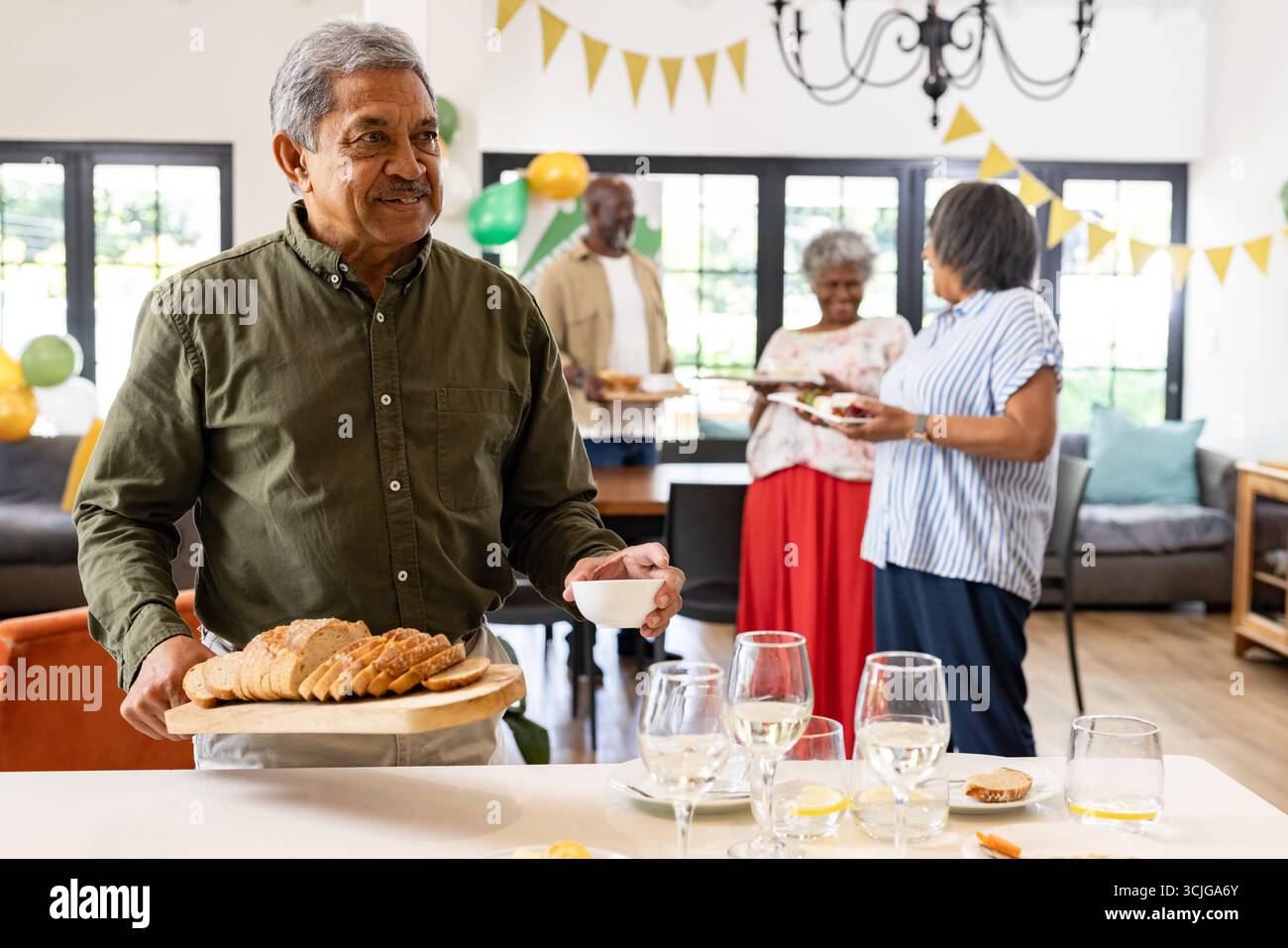 Lächelnder Mann, der Brot und Kaffee bei Familientreffen im gemütlichen Wohnzimmer serviert Stockfoto