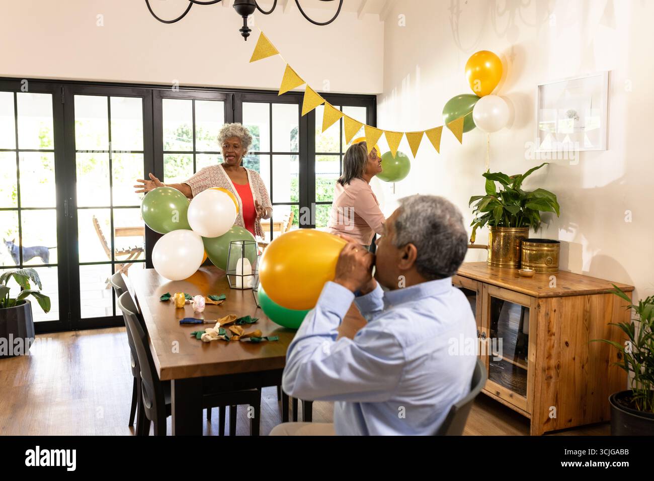 Dekoration für Partys, verschiedene Gruppen, die Ballons aufblasen und Banner zu Hause aufhängen Stockfoto