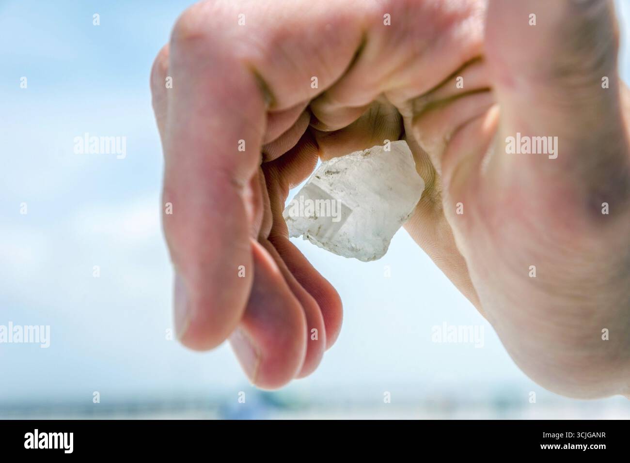 Halten große Salzkristall in der hand gegen blauen Himmel Stockfoto