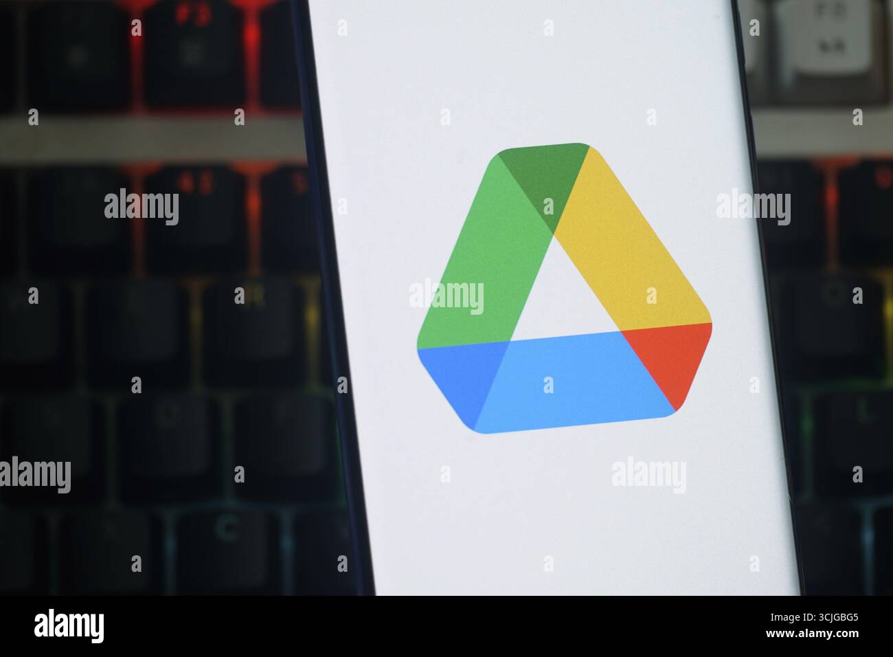 Das Google Drive-Logo wird auf einem Smartphone-Bildschirm auf einer schwach beleuchteten Tastatur angezeigt Stockfoto