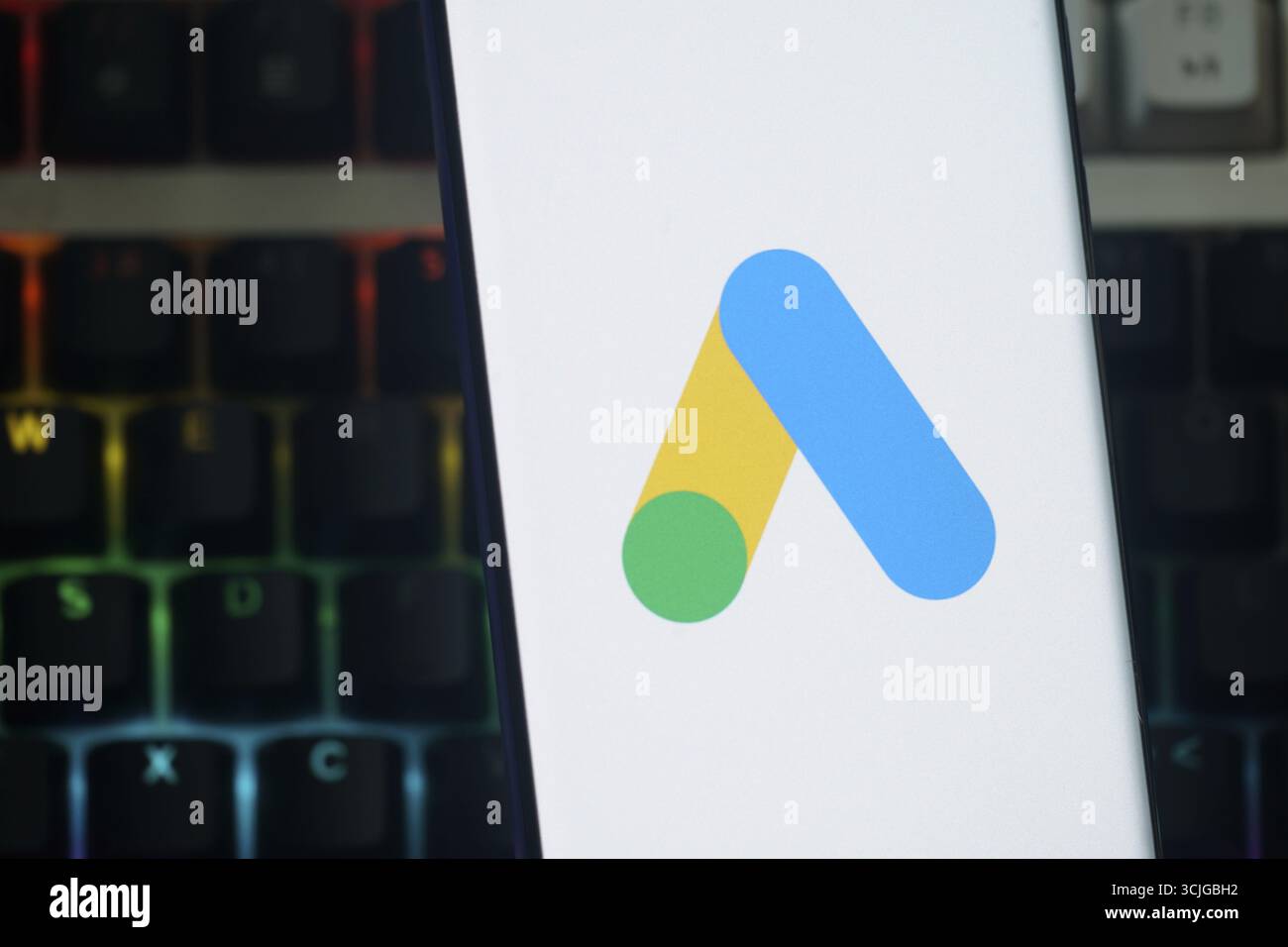 Google Ads-Logo wird auf einem Smartphone-Bildschirm mit einer farbigen Tastatur im Hintergrund angezeigt Stockfoto