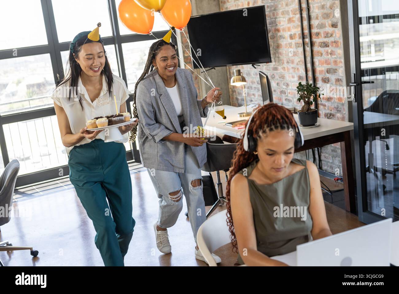 Feiert Geburtstag im Büro, Kollegen mit Cupcakes und Ballons, lächelt fröhlich Stockfoto
