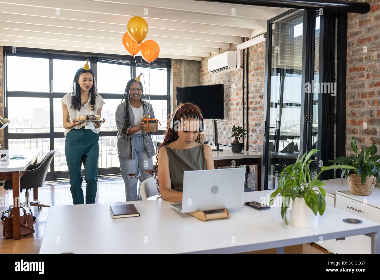 Kollegen überraschen Frau mit Kuchen und Ballons bei moderner Bürofeier Stockfoto