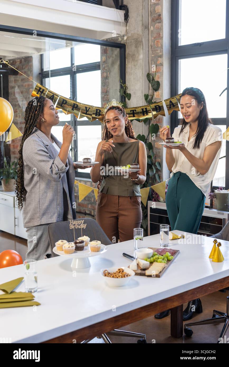 Kollegen genießen Geburtstagsfeier mit Kuchen und Dekorationen im modernen Büro Stockfoto