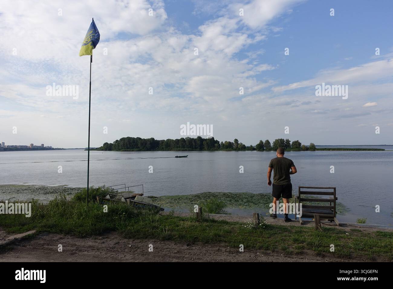 Ein Mann und eine ukrainische Flagge in der Nähe eines Sees in der Region Kiew Stockfoto