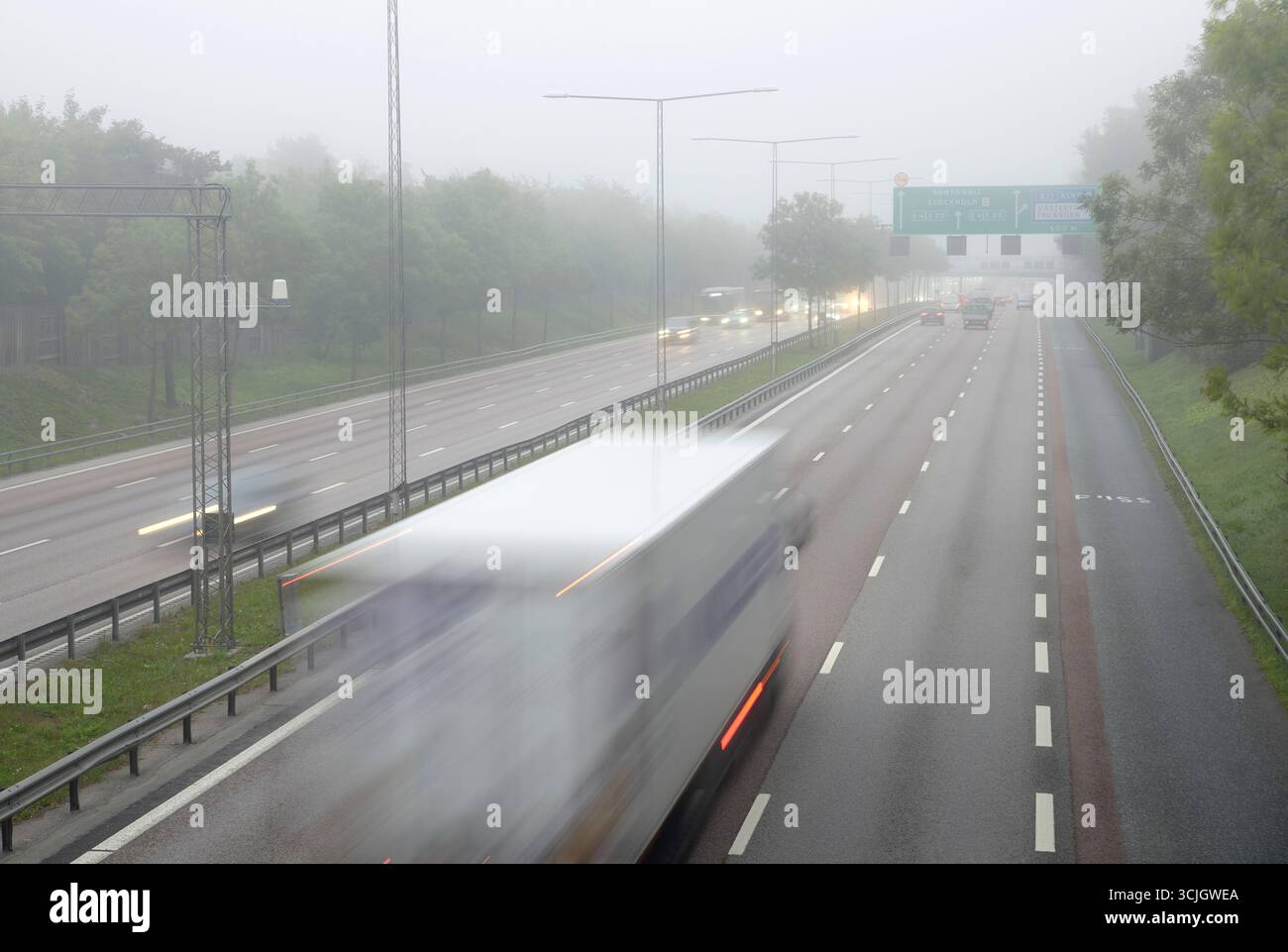 Autos auf nebeliger Autobahn mit Straßenschildern in Richtung Sundsvall und Stockholm Stockfoto