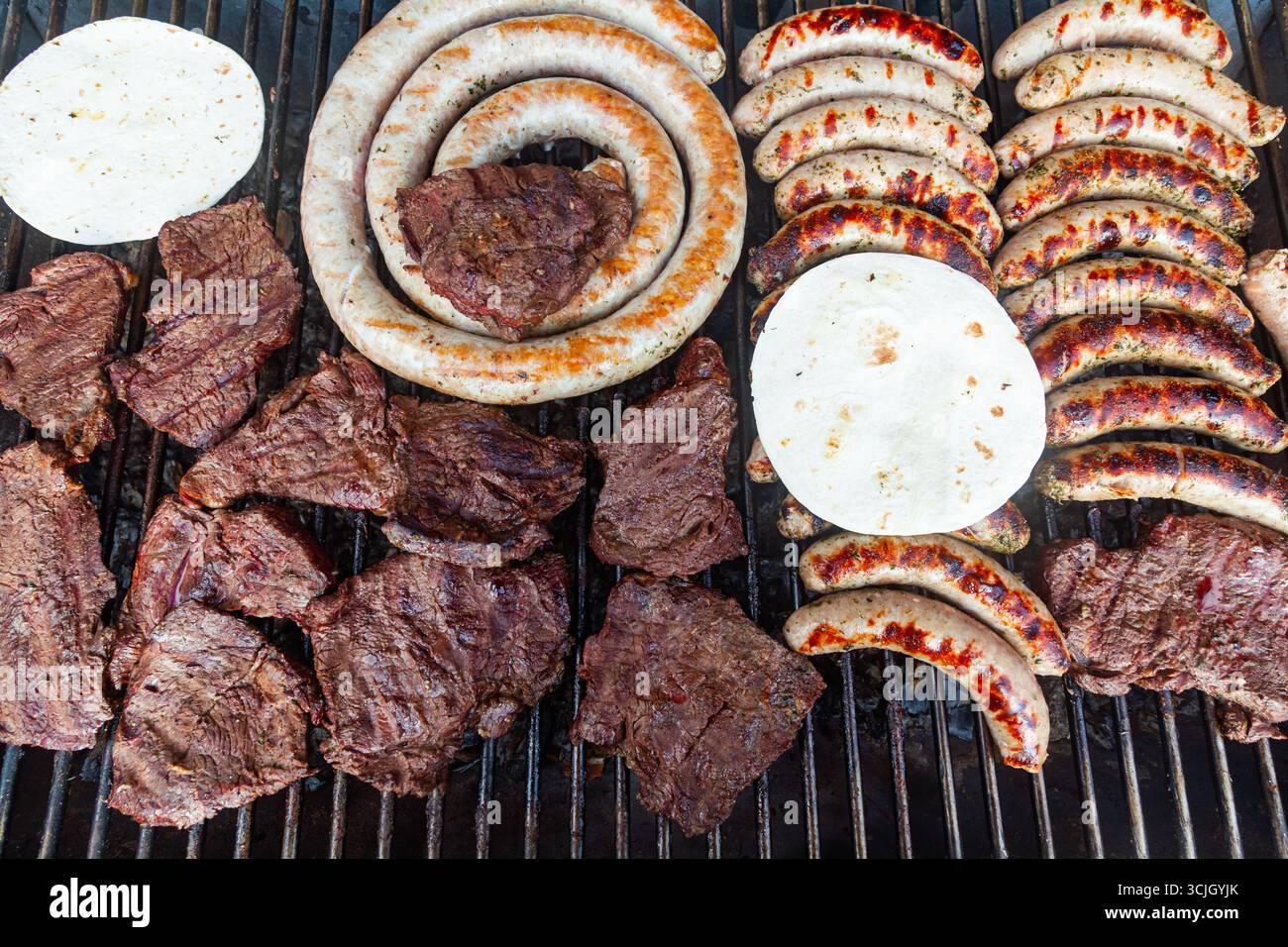 Fleischsteaks mit Würstchen und Fladenbrot drauf. Stockfoto