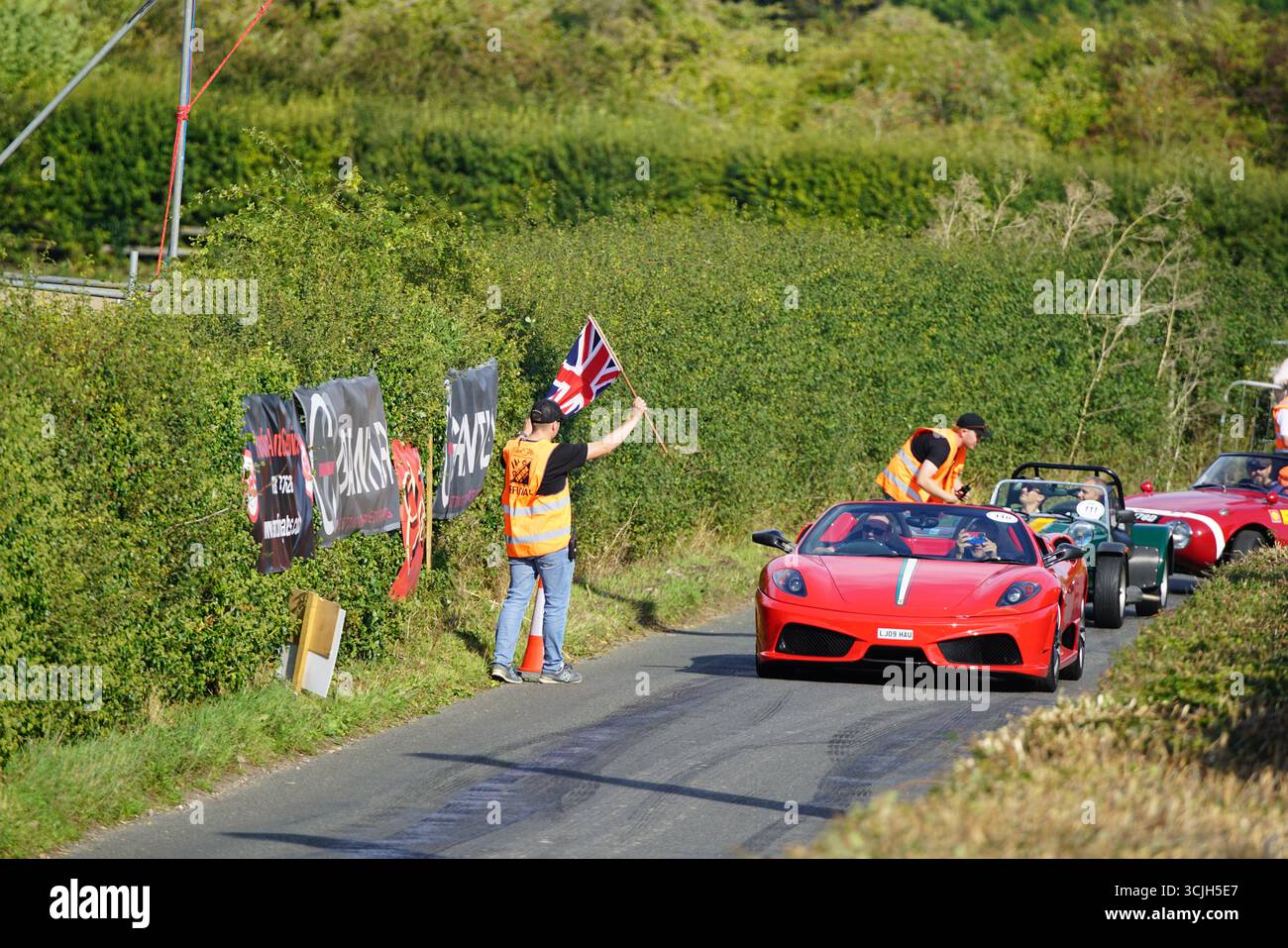 Klassische und Sportwagen auf einer malerischen Straße während eines Rennsports. Shere Hill Climb, East Clandon, Guildford Stockfoto