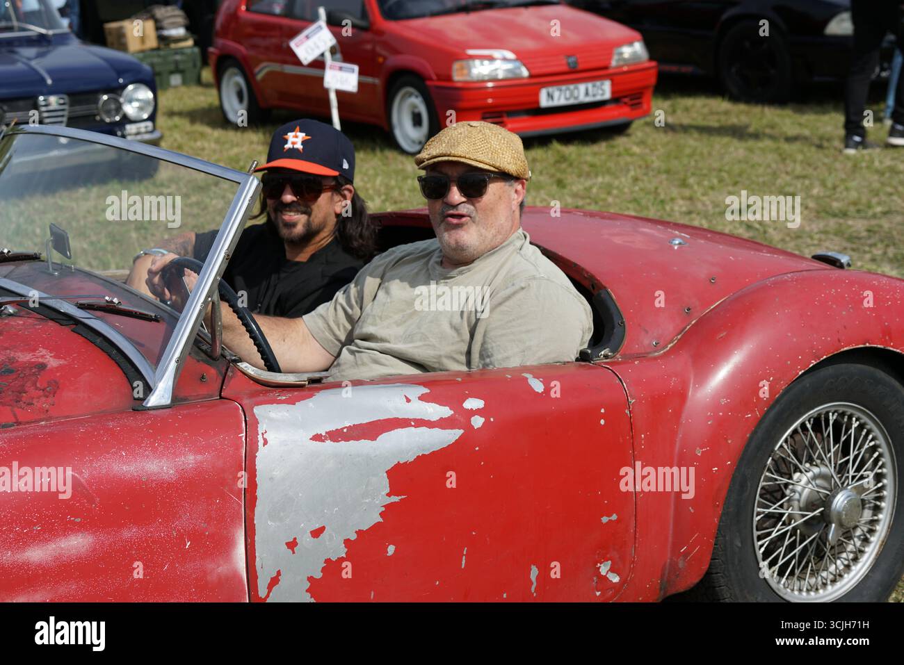 Oldtimer-Fahrt mit zwei lächelnden Freunden bei einem Outdoor-Event. Shere Hill Climb, East Clandon, Guildford Stockfoto