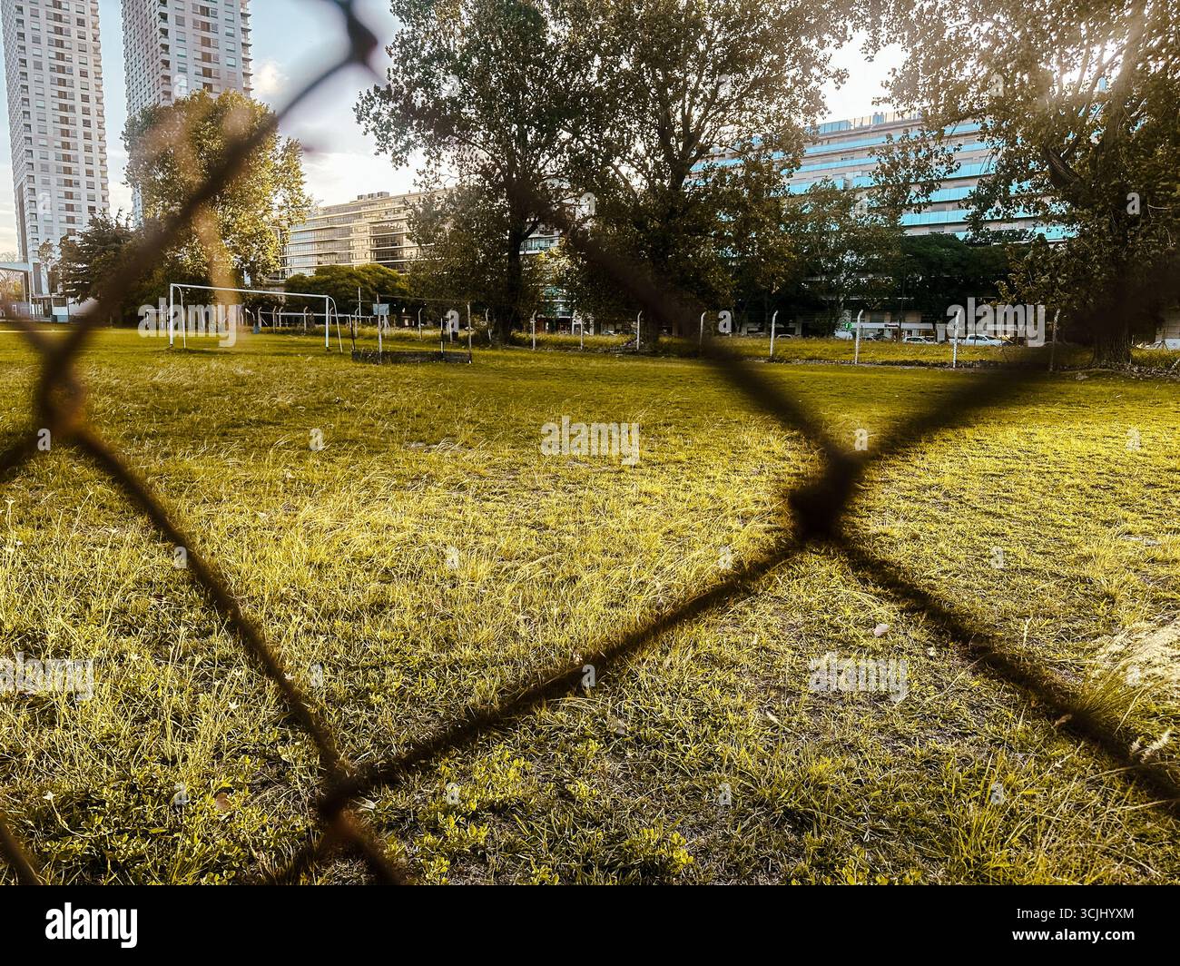 Buenos Aires, Argentinien – 22. Dezember 2022: Blick durch einen Zaun auf ein leeres städtisches Fußballfeld in Puerto Madero, umgeben von Stadtbäumen und Hochhäusern Stockfoto