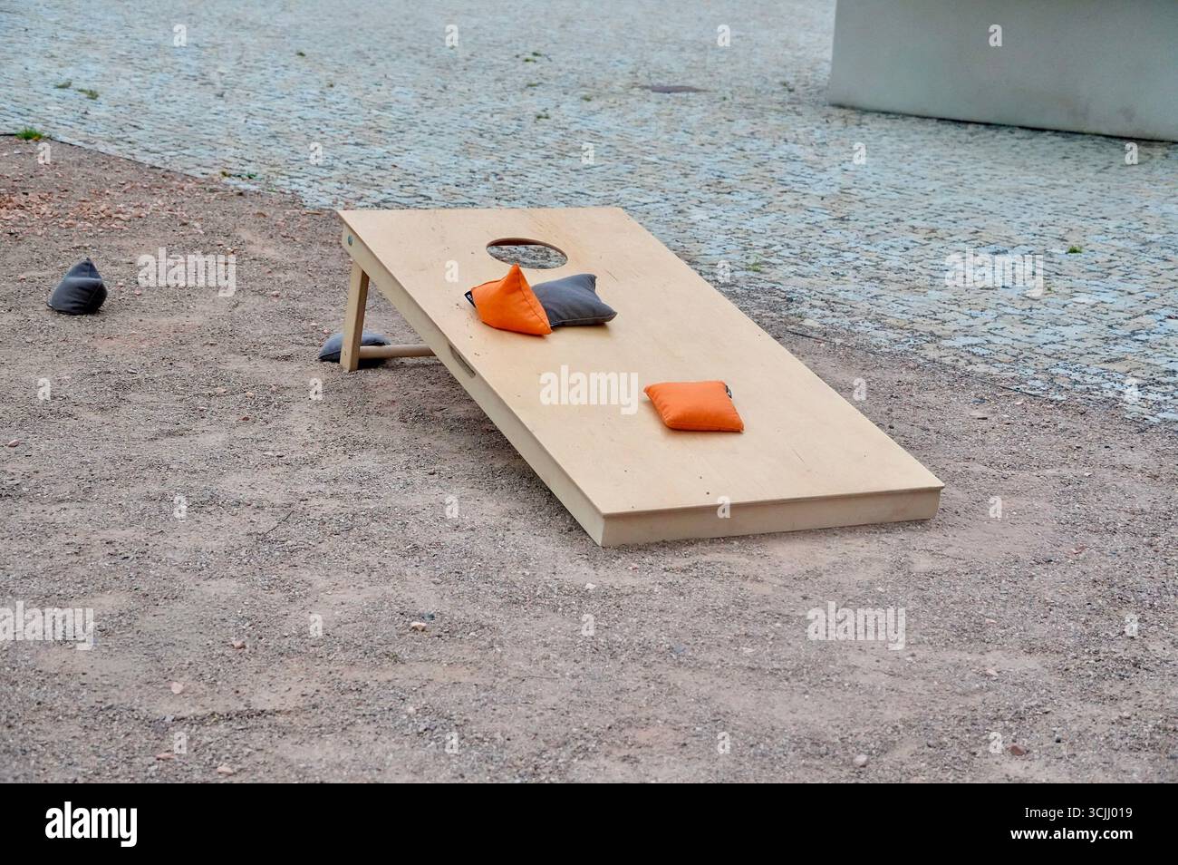 Holzbank mit orangefarbenen Kissen auf dem Boden im Park Stockfoto