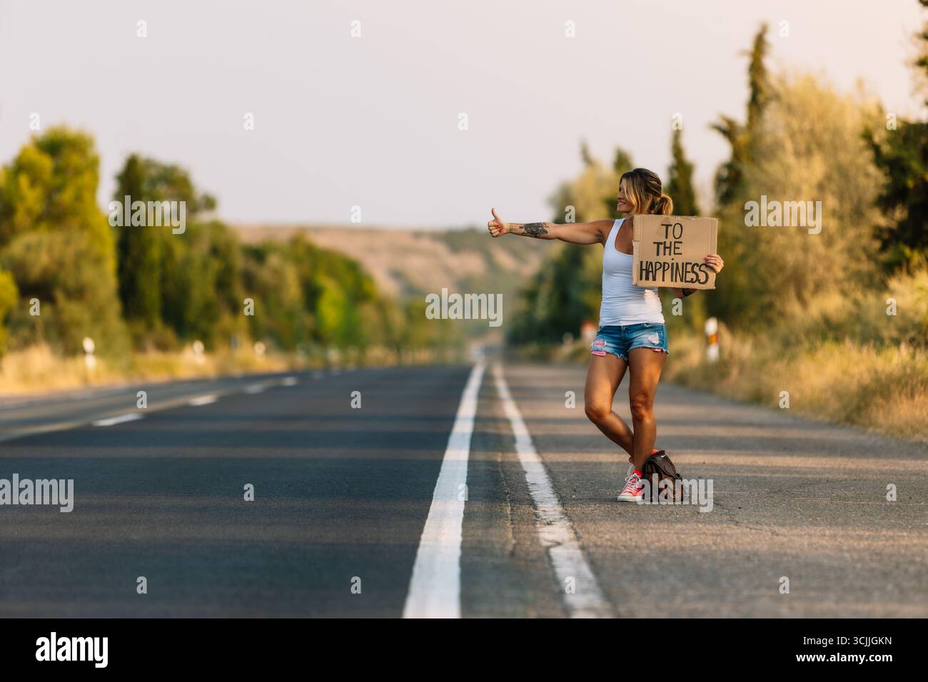 Touristen per Anhalter auf einer Landstraße auf der Suche nach Glück Stockfoto
