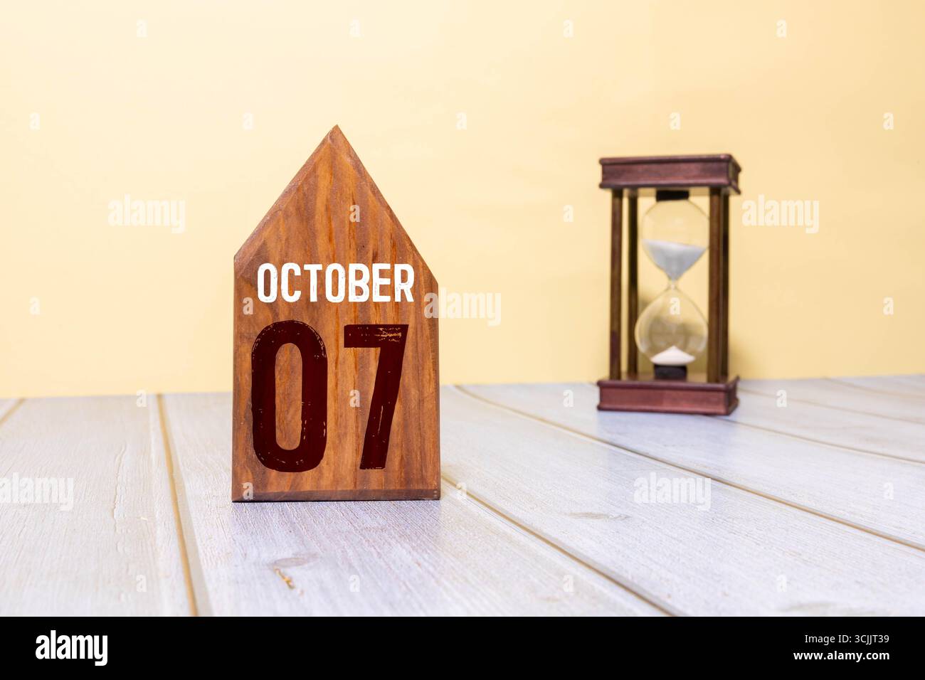 Holzkalender mit Datum vom 07. oktober und dekorativer Pflanze auf dem Tisch Stockfoto