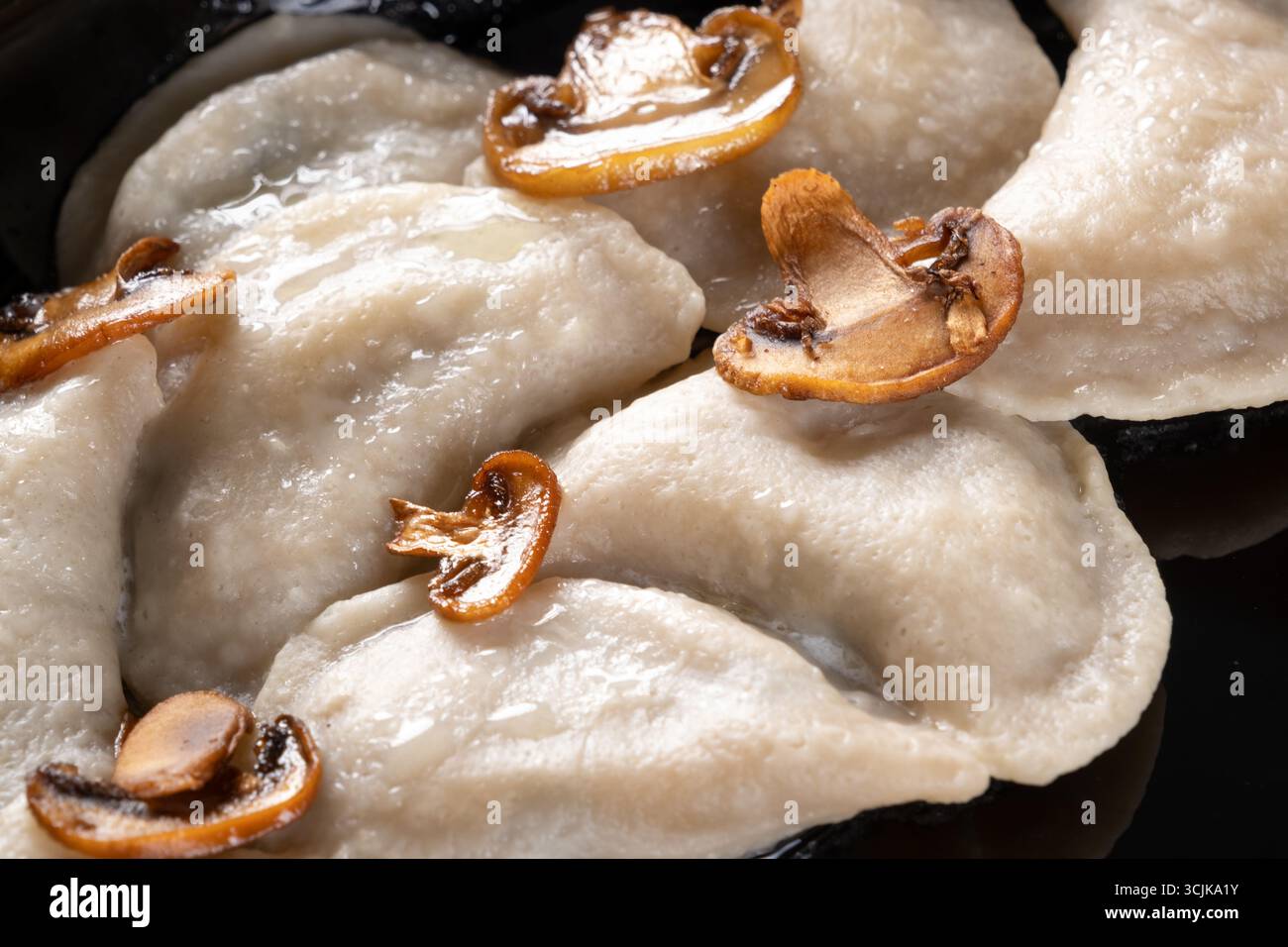 Ein Foto mit Vareniki, einem traditionellen ukrainischen Knödel, präsentiert mit einer herzhaften Füllung und serviert mit einem Klecks Sauerrahm und Kräutern Stockfoto