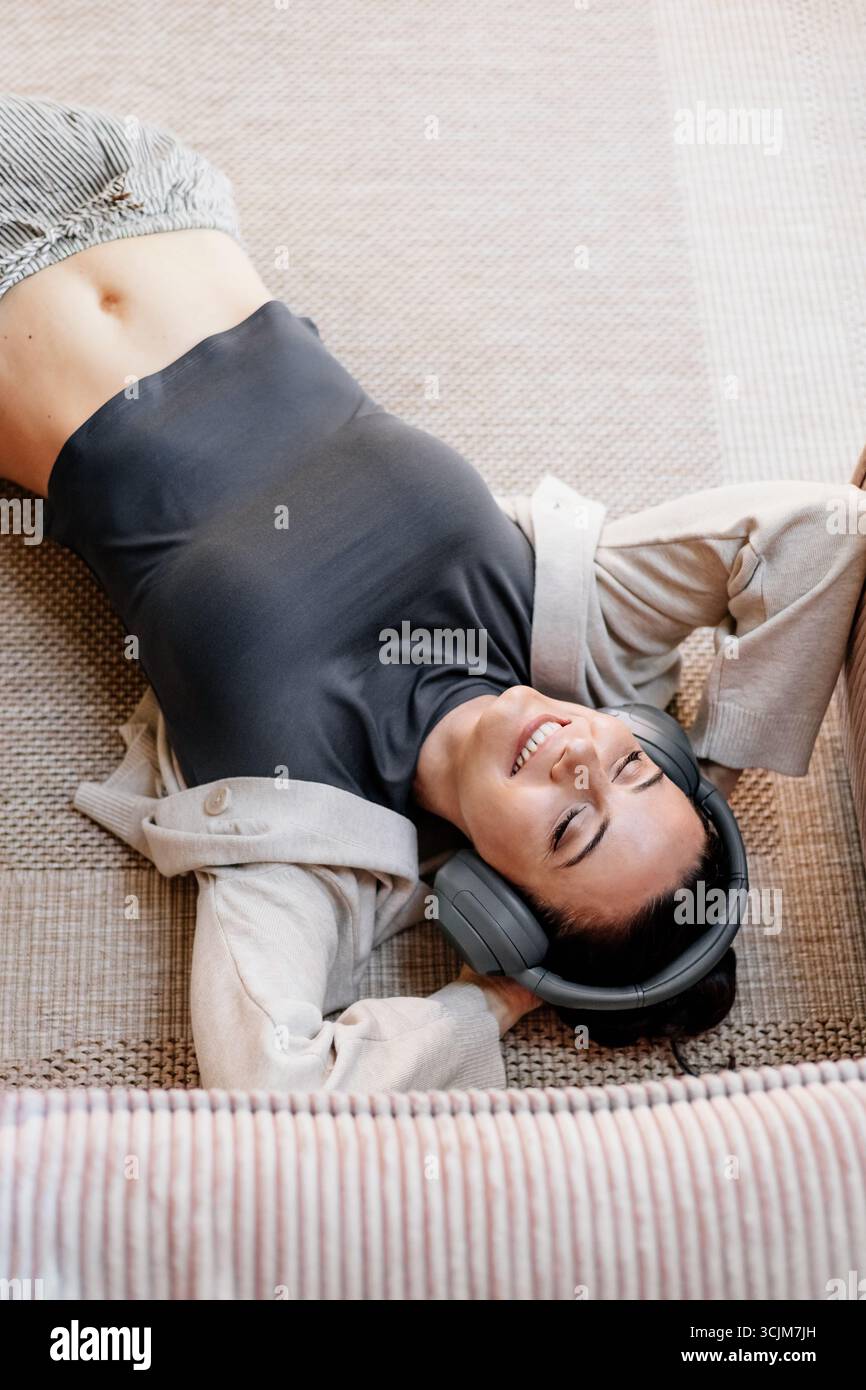 Frau, die sich zu Hause entspannt, Musik nach der Arbeit genießt. Stockfoto