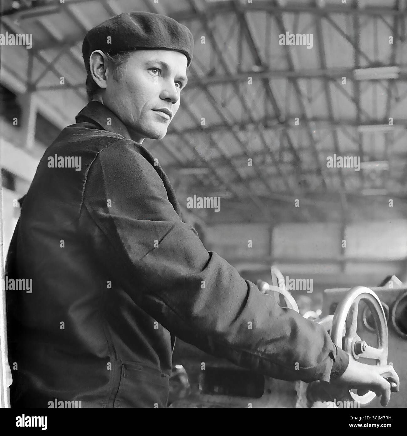 Ein heldenhaftes Porträt eines Arbeiters in einer Baskenmütze an seiner Maschine in einer Werkstatt einer Slawjansk-Fabrik, 1974. Dieses Bild im Stil des kanonischen sozialistischen Realismus fängt den selbstbewussten, zukunftsweisenden Blick eines Arbeiters ein und ist ein Symbol für industrielle Macht, die Verherrlichung der Arbeiterklasse in der Stagnation-Ära und den kreativen Geist eines friedlichen Donbass Stockfoto