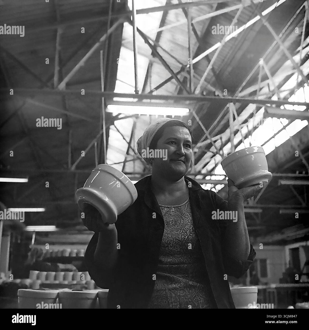 Ein heldenhaftes Porträt einer Arbeiterin der Keramikfabrik Slawjansk, die stolz Fertigprodukte zeigt, 1976. Diese monumentale Aufnahme im Stil des sozialistischen Realismus, die in einer Werkstatt der Stagnation-Ära aufgenommen wurde, ist ein Symbol für die Verherrlichung der arbeitenden Person, den „Fünfjahresplan der Qualität“ und die kreative Kraft eines friedlichen Donbas Stockfoto