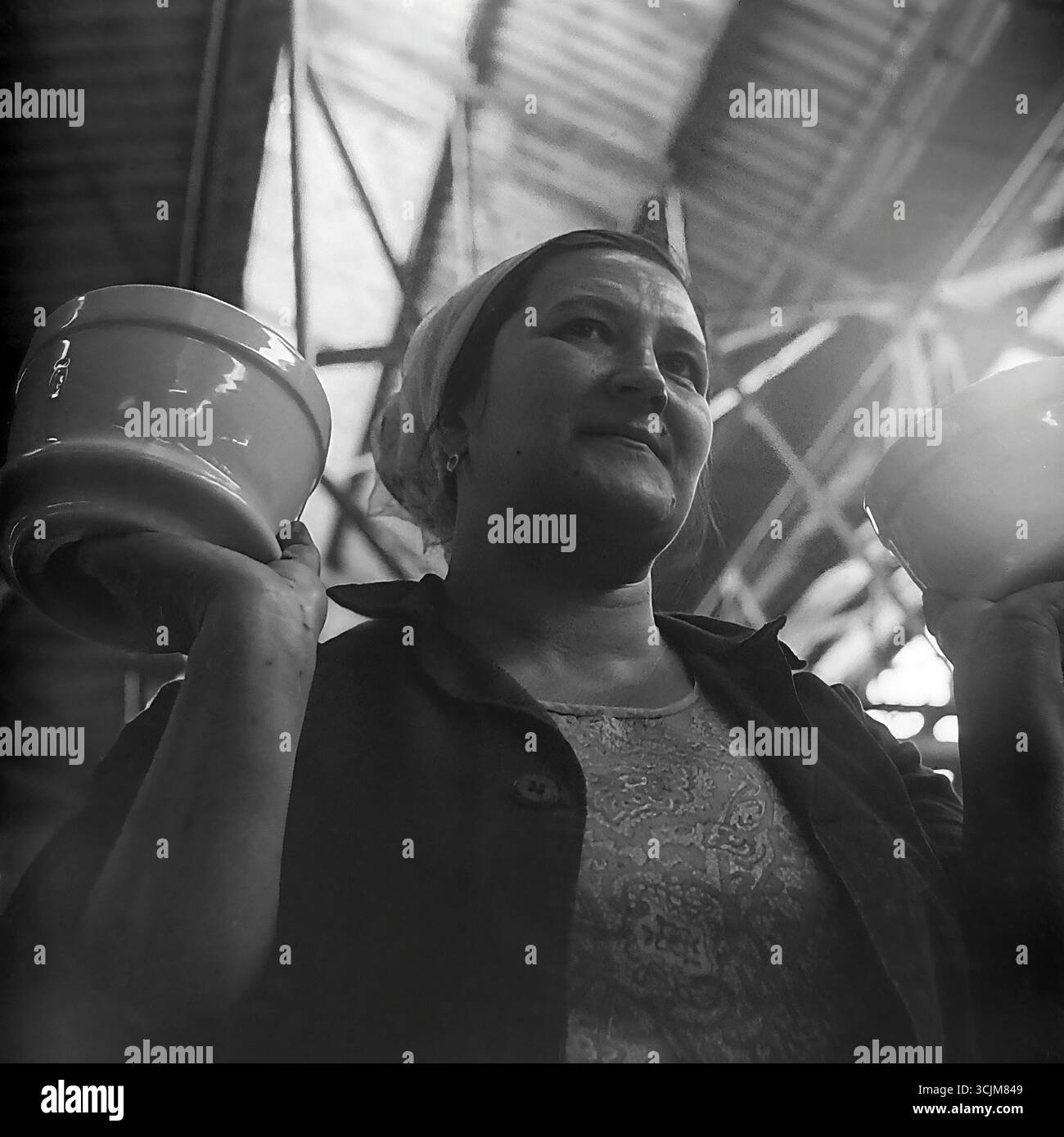 Ein heldenhaftes Porträt einer Arbeiterin der Keramikfabrik Slawjansk, die stolz Fertigprodukte zeigt, 1976. Diese monumentale Aufnahme im Stil des sozialistischen Realismus, die in einer Werkstatt der Stagnation-Ära aufgenommen wurde, ist ein Symbol für die Verherrlichung der arbeitenden Person, den „Fünfjahresplan der Qualität“ und die kreative Kraft eines friedlichen Donbas Stockfoto