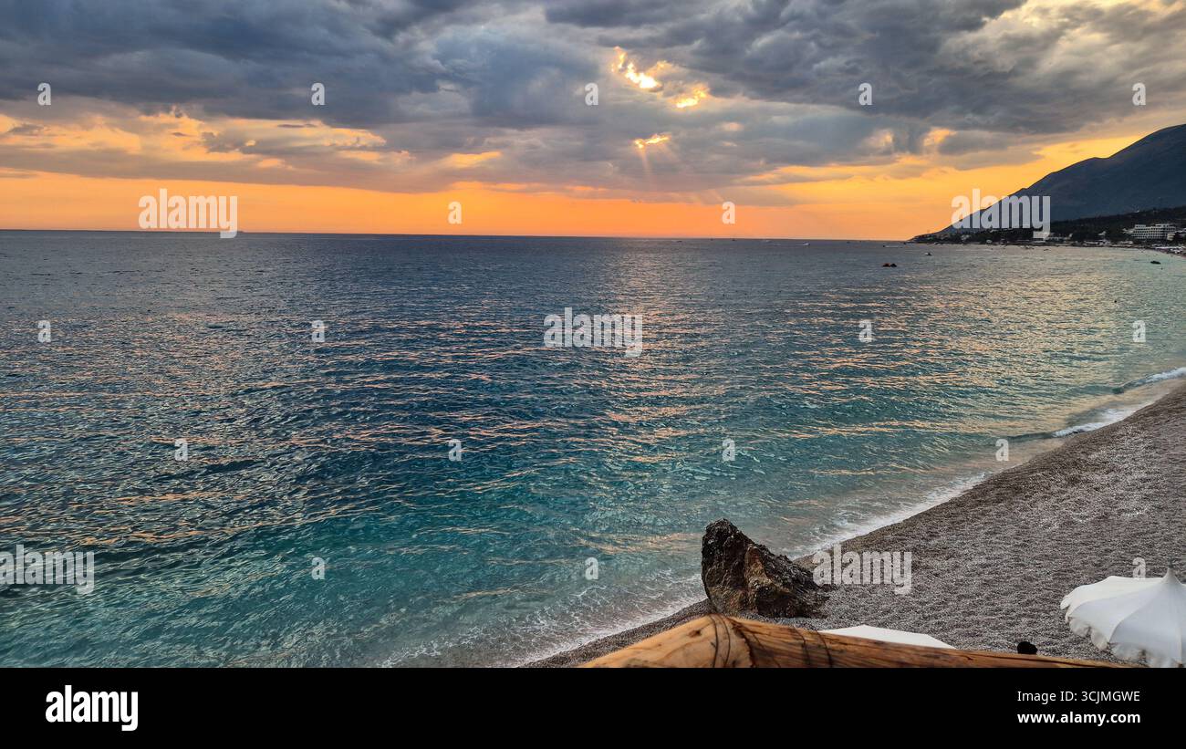 Dramatischer Sonnenuntergang über dem Ionischen Meer vom Strand Dhërmi an einem bewölkten Sommerabend an der albanischen Riviera. Stockfoto