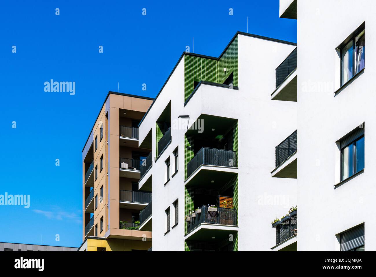 Moderner Wohnkomplex mit verschiedenen Apartmentgebäuden, Balkonen und urbanem Design unter hellblauem Himmel. Stockfoto