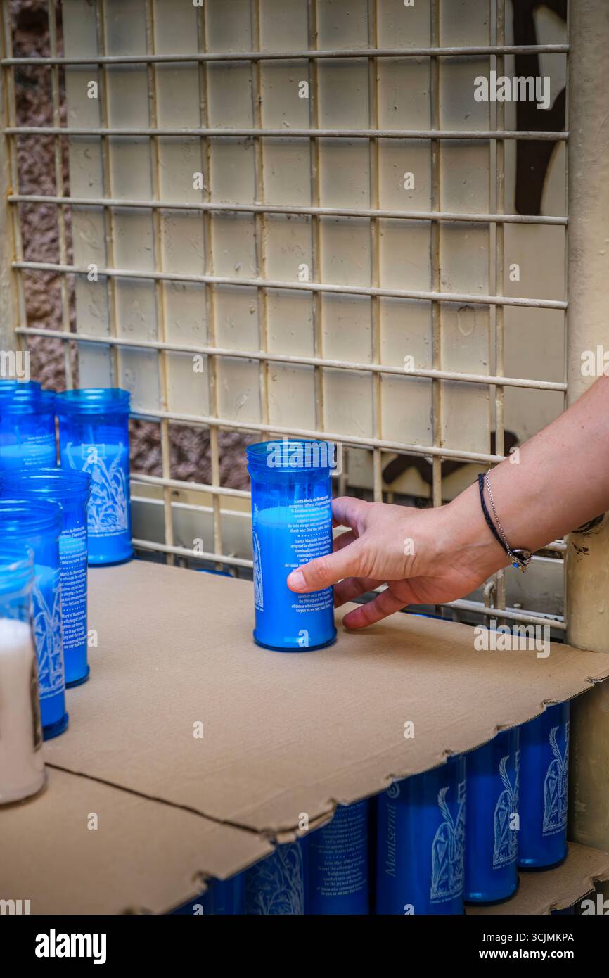Pilger Hellen Sie traditionelle blaue Votivkerzen während eines religiösen Besuchs im Kloster Montserrat an. Heiliges Ritual, spirituelle Verehrung, katholische Pilgerreise, Stockfoto