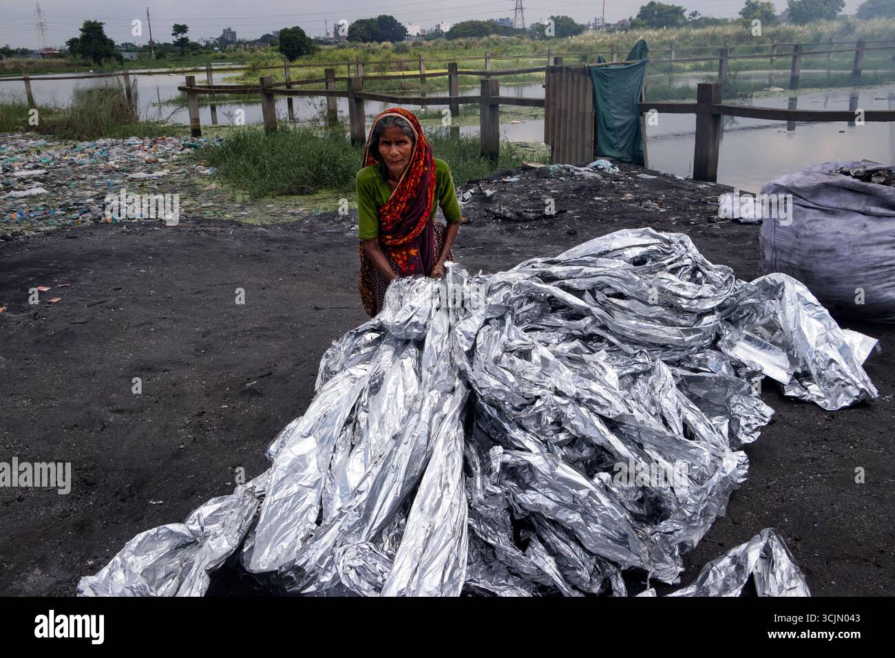 Dhaka, Dhaka, Bangladesch. September 2025. Am Stadtrand von Dhaka, Bangladesch, leiden informelle Recyclingarbeiter unter gefährlichen Bedingungen, um wiederverwendbare Materialien aus Aluminiumfolie zu extrahieren. Bei diesem Prozess werden Folien aus Industrie- und Hausmüllströmen in provisorischen Schornsteinen verbrannt. Diese Praxis bietet den Arbeitnehmern zwar einen Lebensunterhalt, stellt aber aufgrund giftiger Emissionen und fehlender Sicherheitsmaßnahmen erhebliche Risiken für die menschliche Gesundheit und die Umwelt dar. Die Arbeiter, oft ungeschützt, arbeiten in einer Umgebung, die mit giftigem Rauch beladen ist, eine deutliche Erinnerung an den bezahlten Preis b Stockfoto