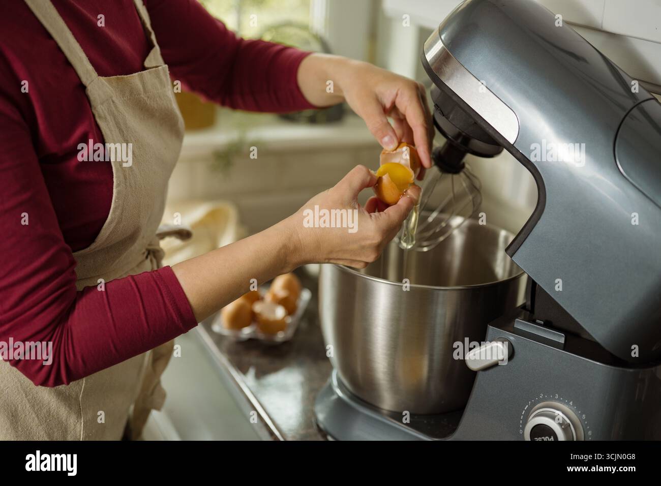 Weibliche Hände brechen das Ei und trennen das Eiweiß vom Eigelb Stockfoto