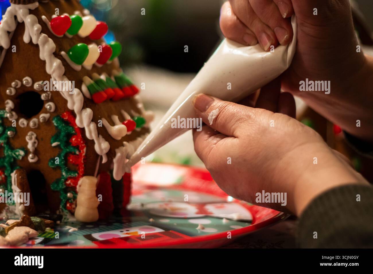 Das Sahnehäubchen wird auf eine Lebkuchenhausecke gepumpt Stockfoto
