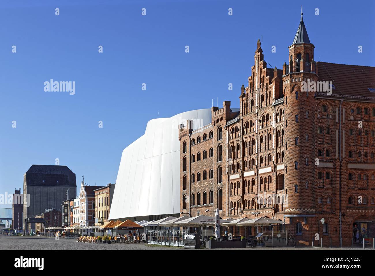 Vorne rechts, mit Türmen versehenes Lagerhaus 1905 und Lagerhaus II 1888, Backsteingebäude, vorne Sitzplätze im Freien, Restaurant, dahinter Ozeaneum Stockfoto