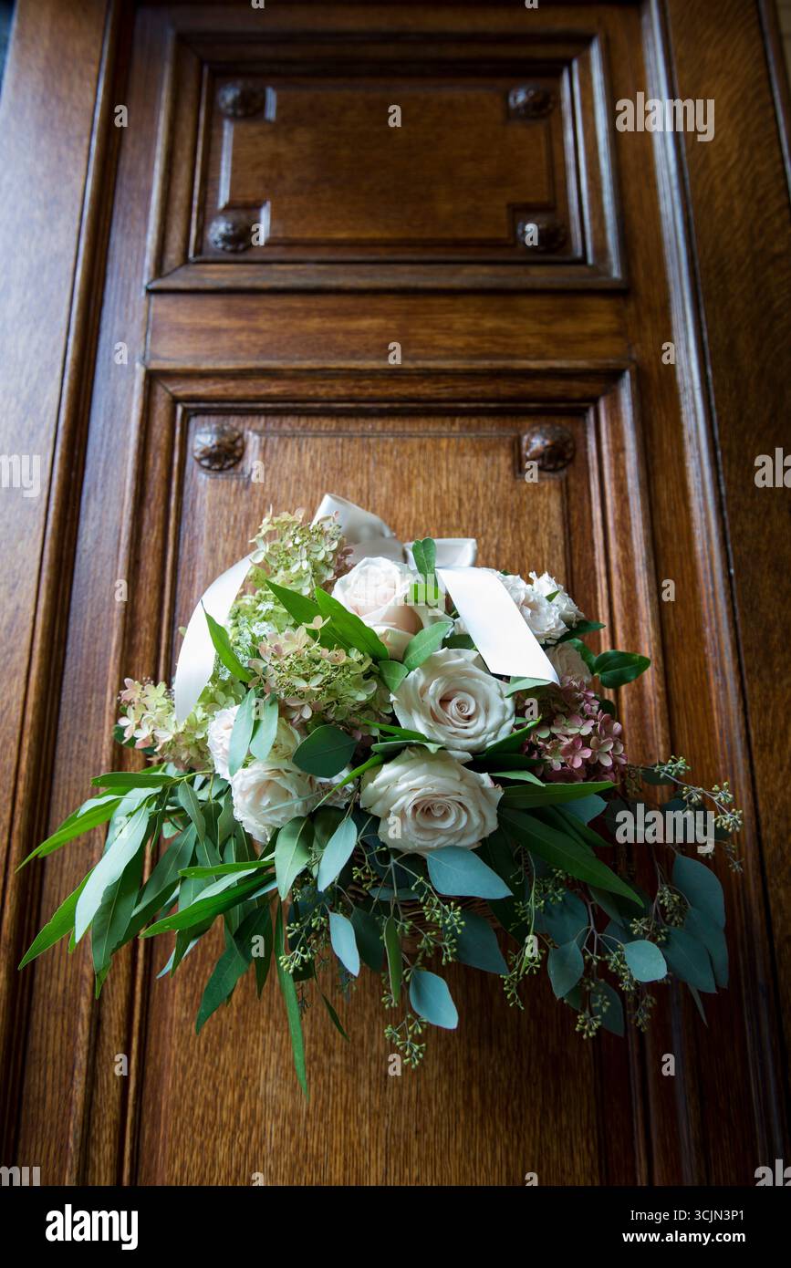 Elegante Blumendekoration in Rose und Grün an der Holztür Stockfoto