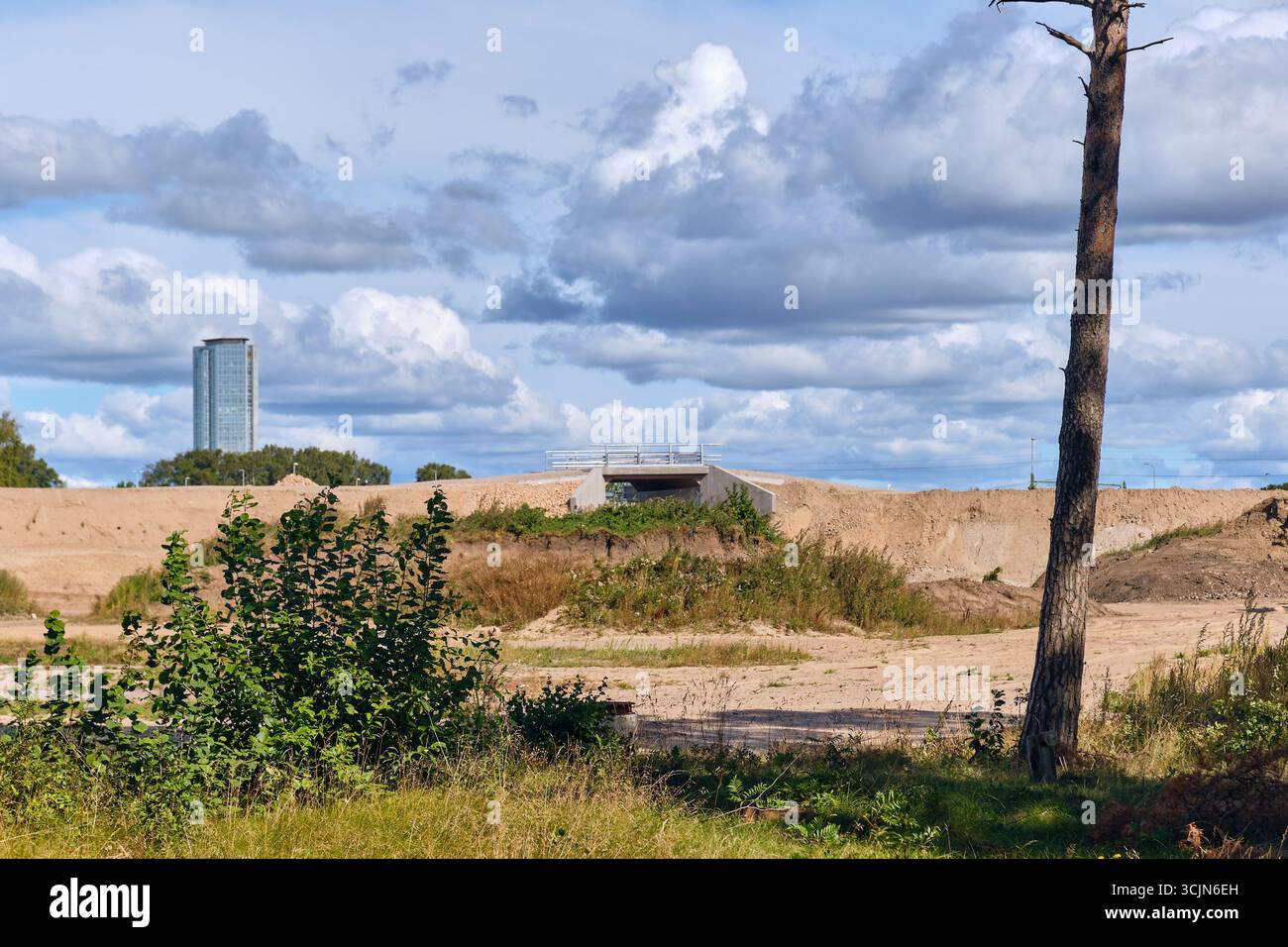 Halmstad, Schweden; 25. August 2023: Sanddamm mit Fußgängerunterführung und hohem Büroturm, der während eines neuen Infrastrukturprojekts in über dem Gebäude ragt Stockfoto