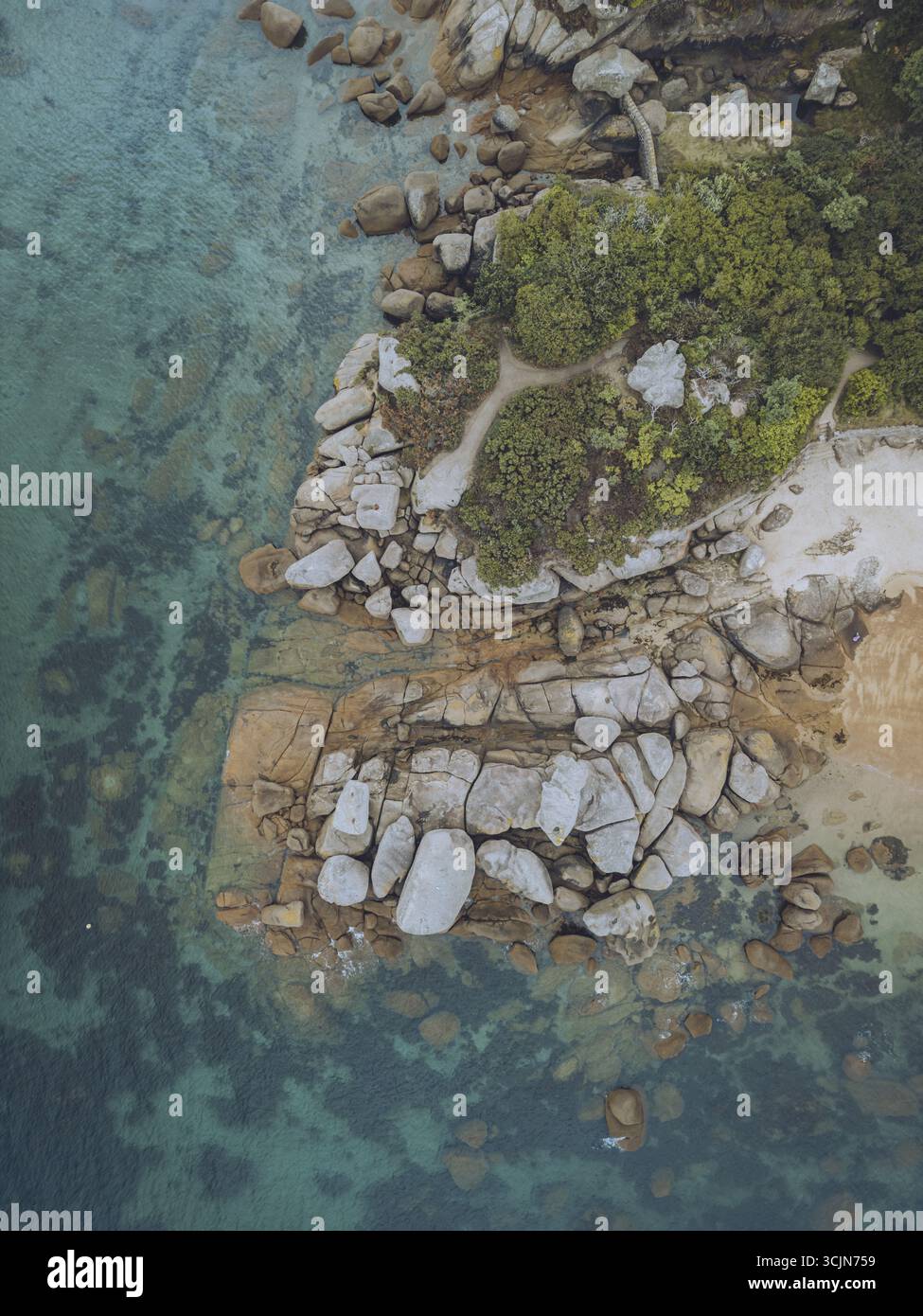 Aus der Vogelperspektive auf die zerklüftete, felsige Küste, wo türkisfarbenes Wasser auf die Küste trifft, zeigt die dramatische Schönheit von Perros-Guirec, Bretagne, Frankreich. Stockfoto