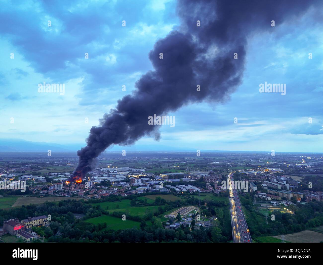 Pianezza, Italien - 4. September 2025: Aus der Luft erhebt sich eine dunkle Wolke hoch über der Euro Stamp-Pflanze, die sich in starkem Kontrast zum Dämmerungshimmel erhebt. Stockfoto