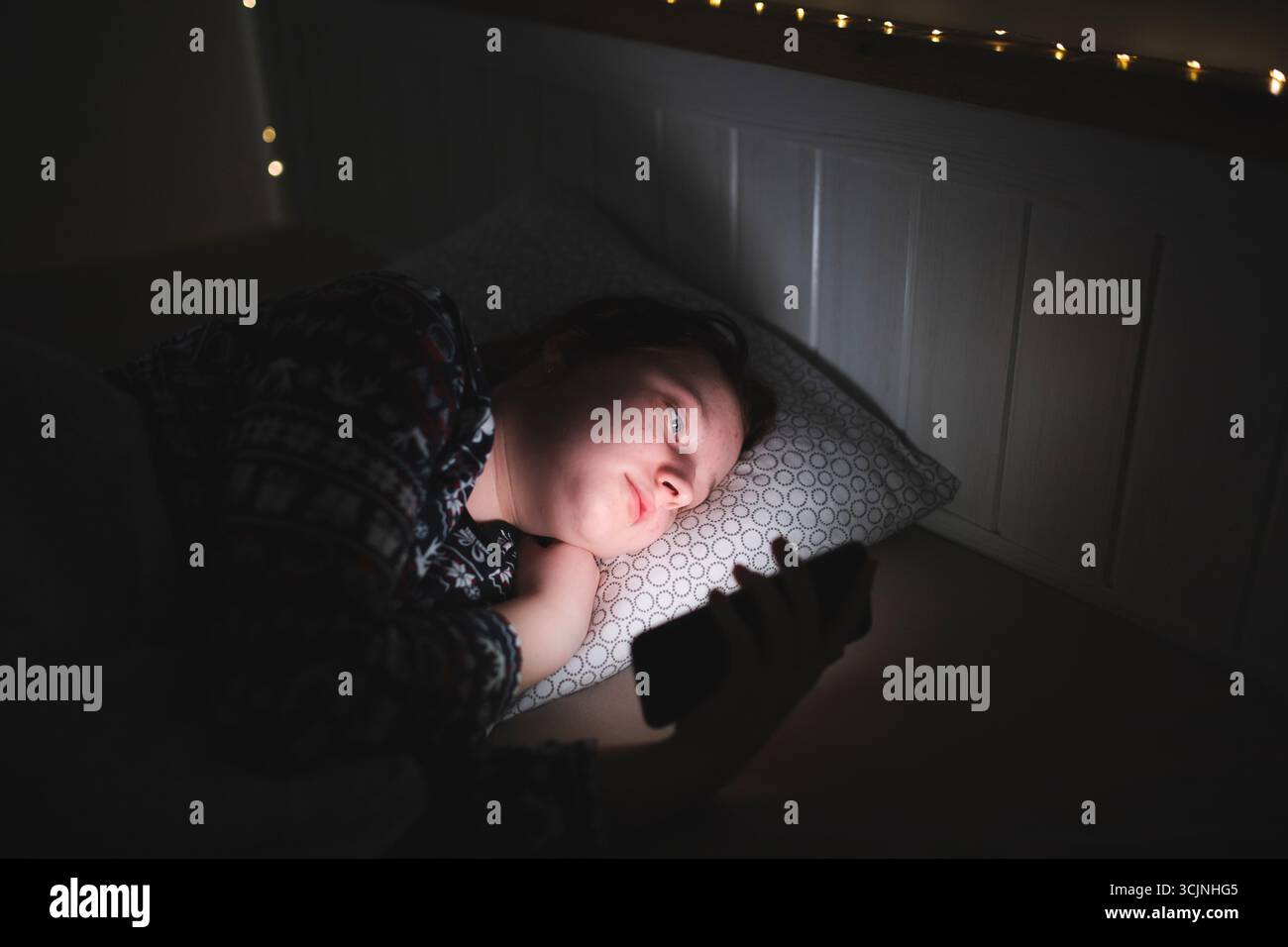 Teenager Mädchen mit Smartphone, Tablet, das spät in der Nacht im Bett liegt. Kinderbildschirm-Suchtkonzept. Stockfoto
