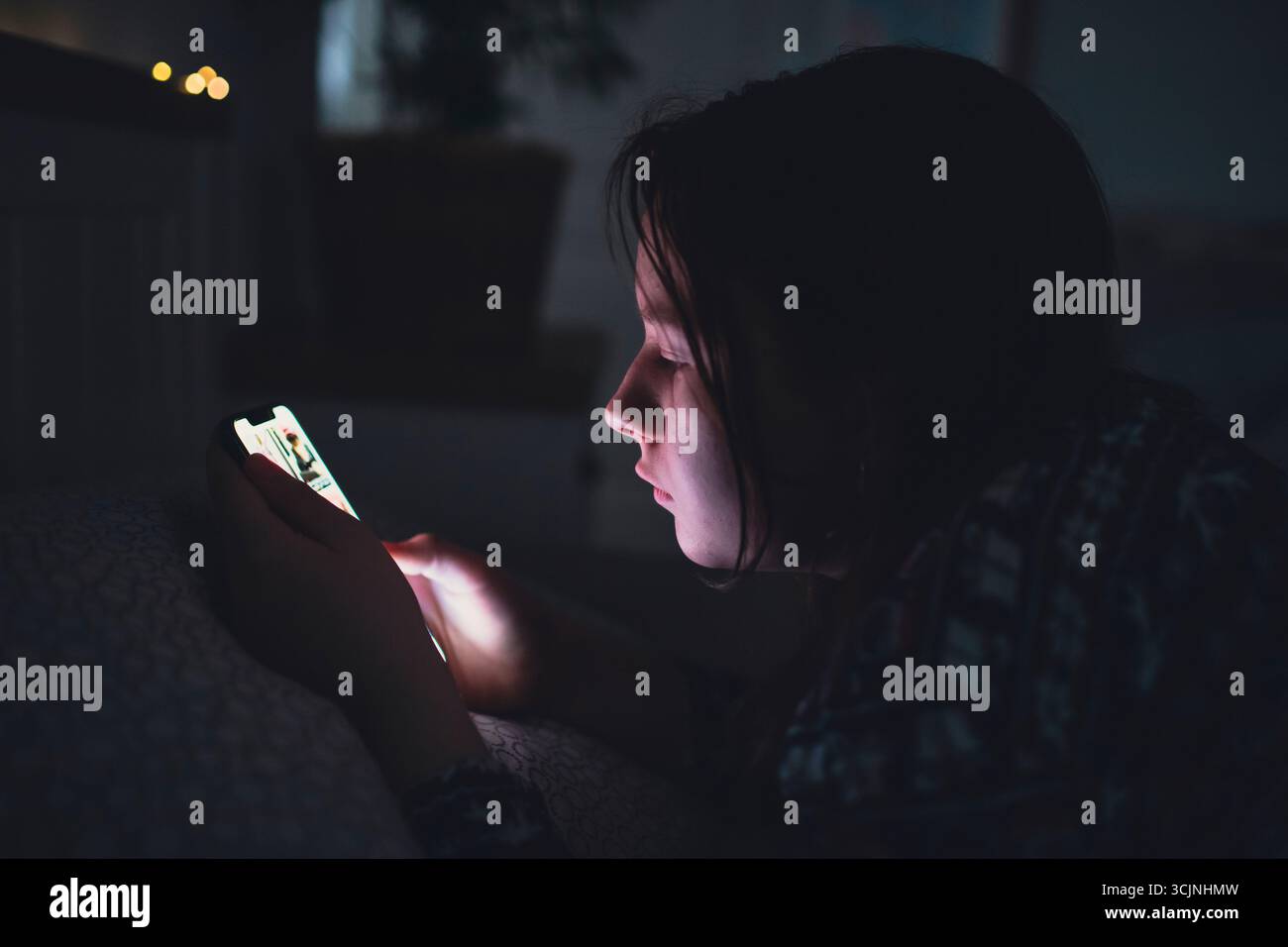 Teenager Mädchen mit Smartphone, Tablet, das spät in der Nacht im Bett liegt. Kinderbildschirm-Suchtkonzept. Stockfoto