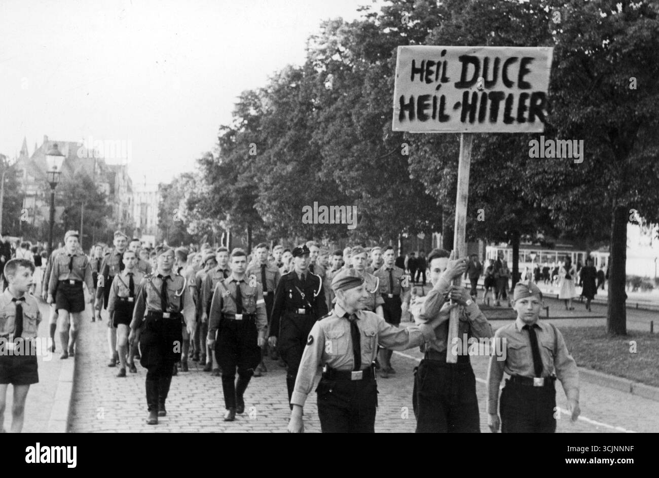 Hitlerjugend – Hitlerjugend marschiert auf einer Stadtstraße. Ein Banner mit der Aufschrift "Heil Duce, heil Hitler" ist sichtbar. 2. Weltkrieg, 1930er Jahre Stockfoto